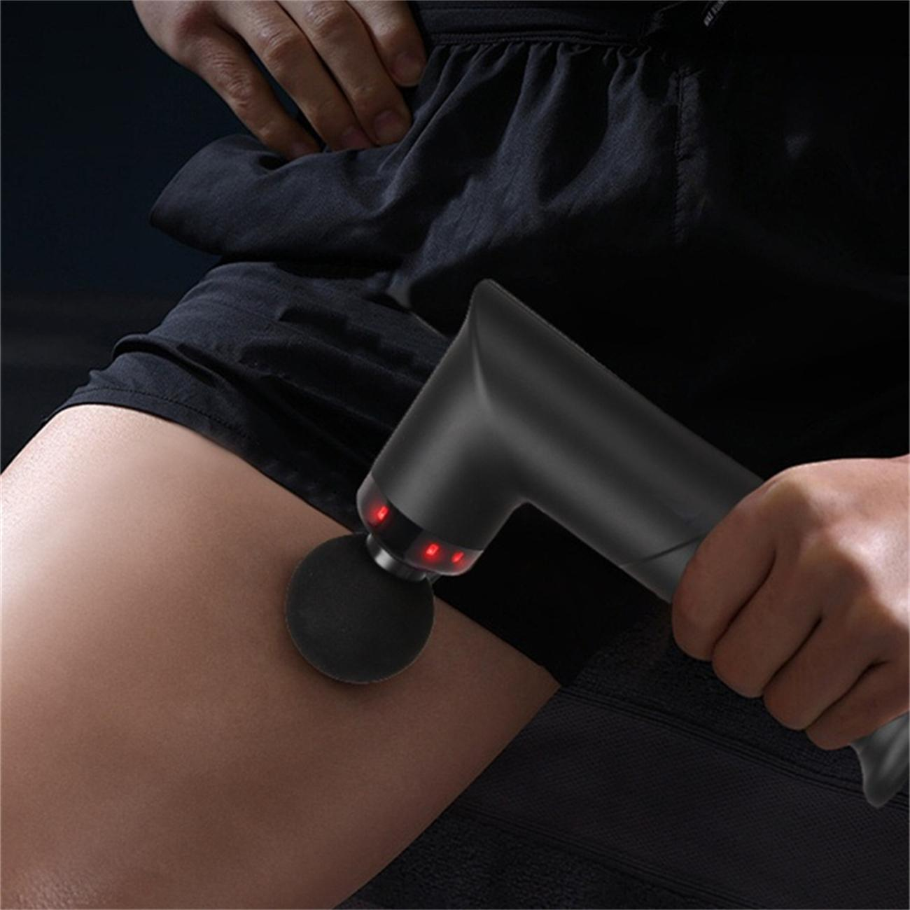 Schwarze Massagepistole am Oberschenkel, rote Lichter am Gerät.