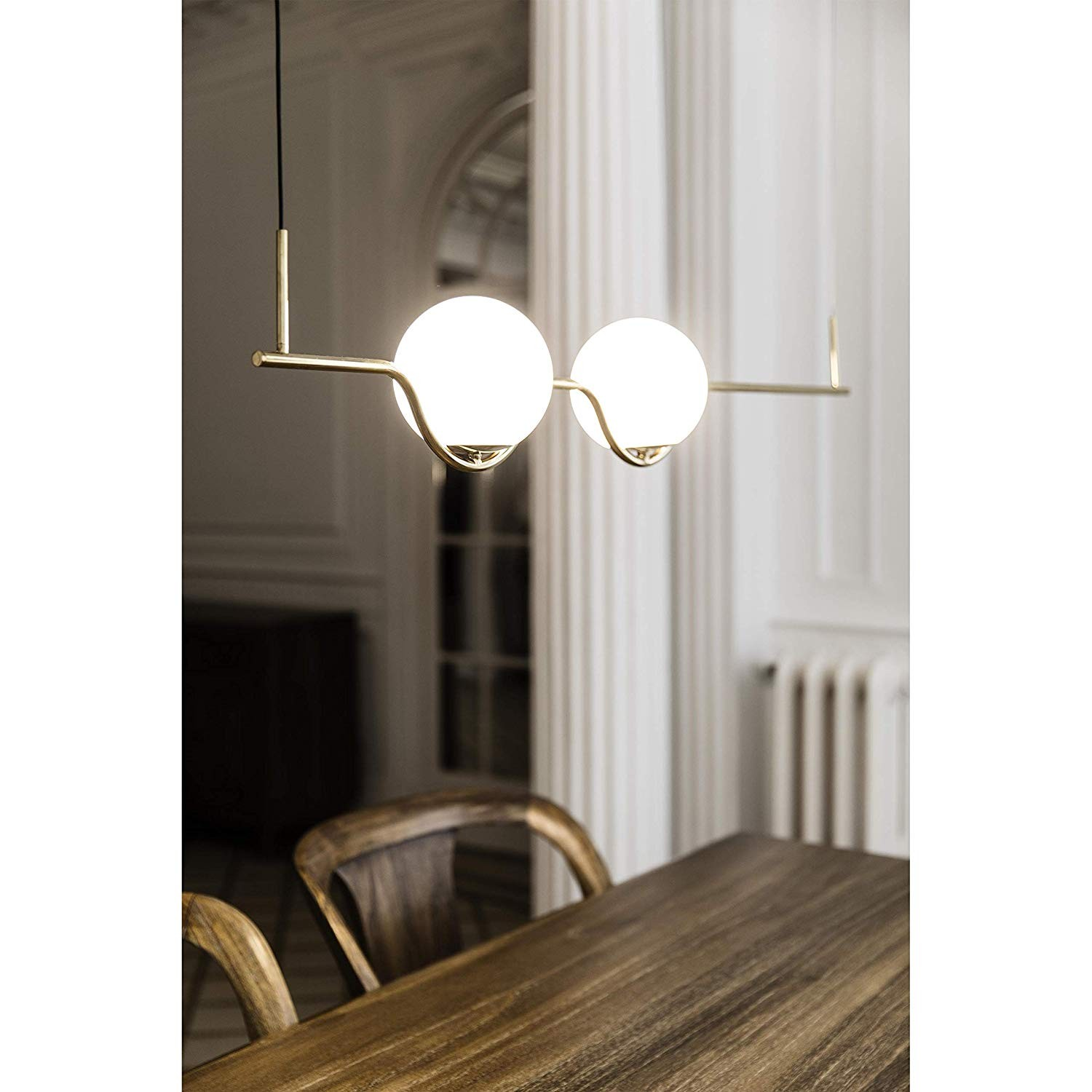 Un lampadario color oro con due luci rotonde è appeso sopra un tavolo di legno.
