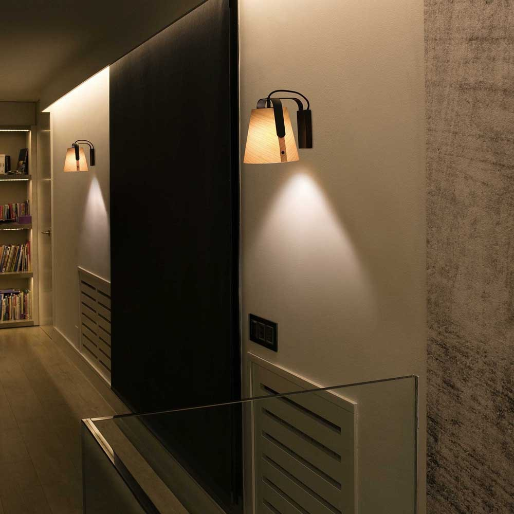 Corridoio con due lampade da parete. Design in legno e nero. La luce si riflette sui muri.