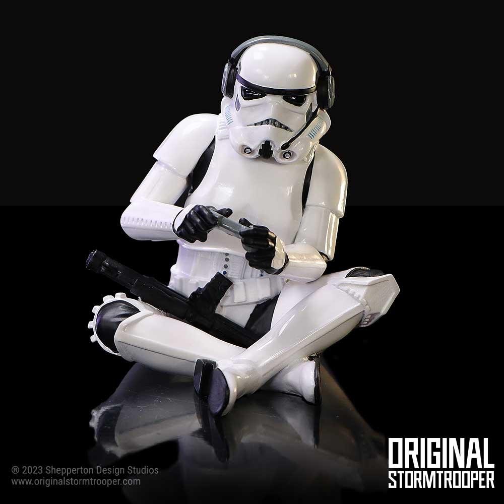 Figura de Stormtrooper sentada, jugando con un mando, fondo negro.