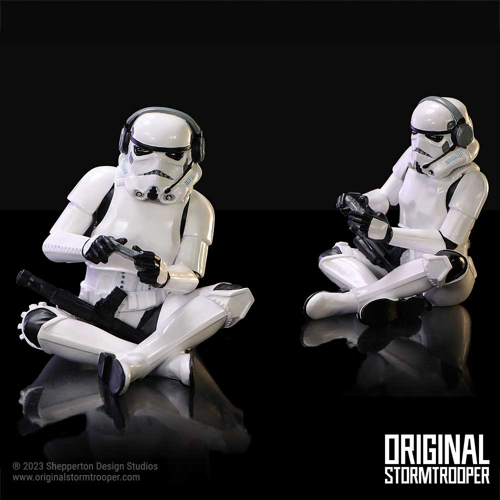 Dos soldados de asalto de Star Wars sentados en una superficie oscura, jugando videojuegos con mandos.