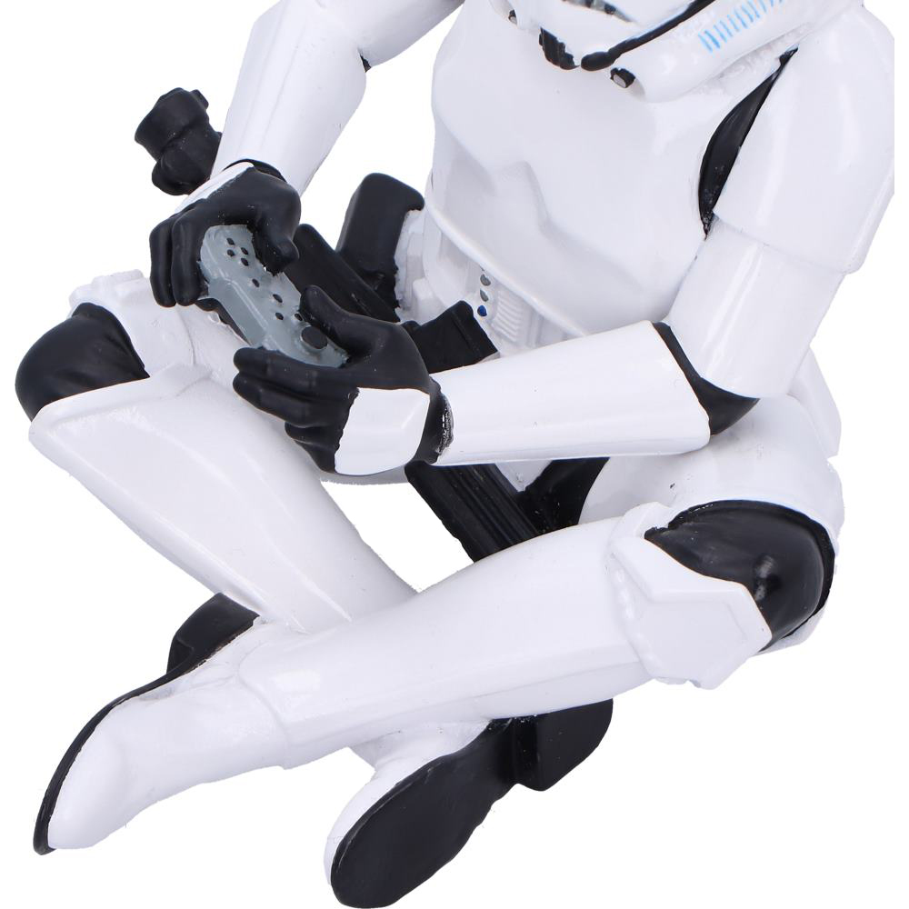 Una figura blanca de Stormtrooper sostiene un controlador gris, sentado en pose dinámica.