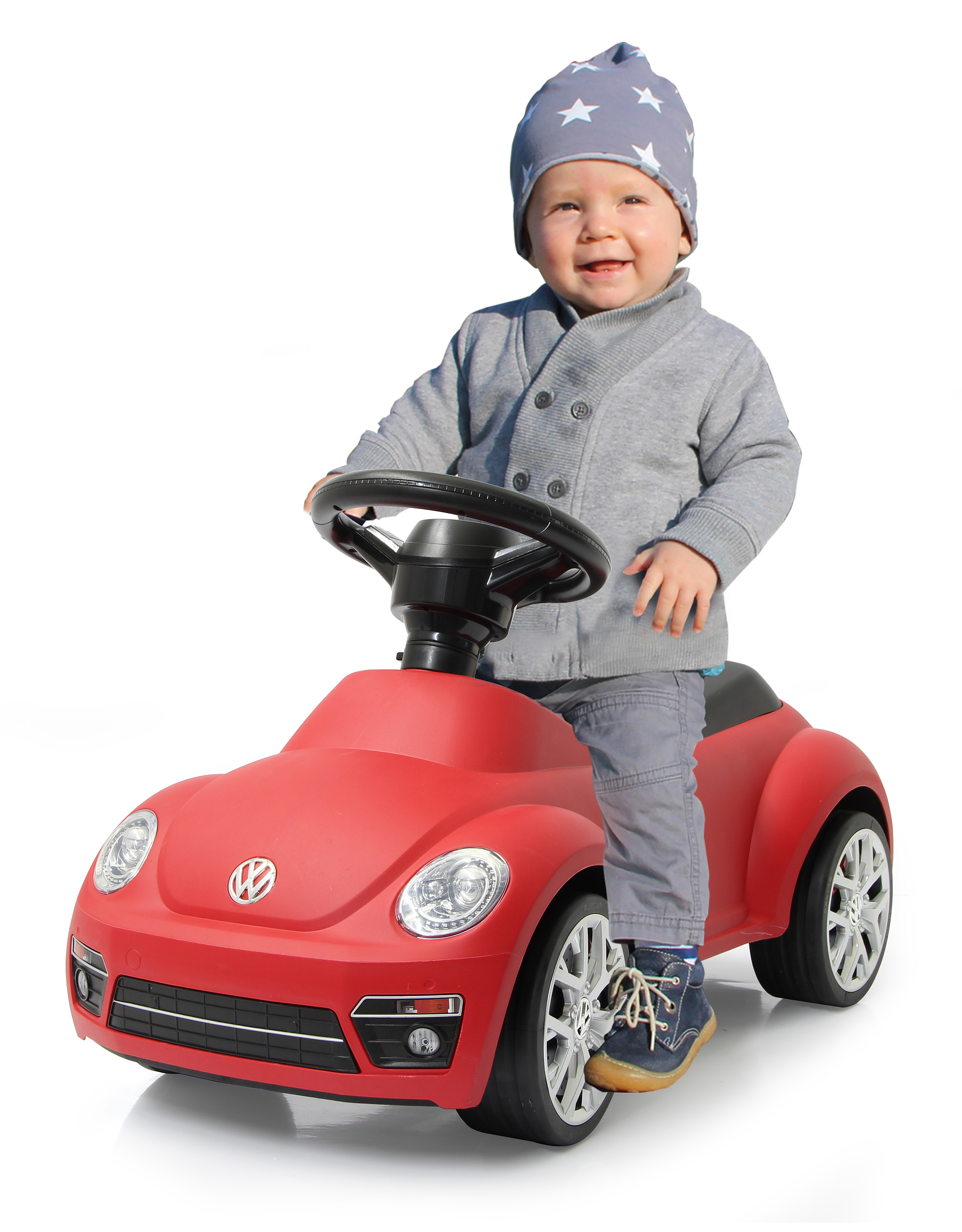 Un bambino seduto su un'auto rossa, sorridente.