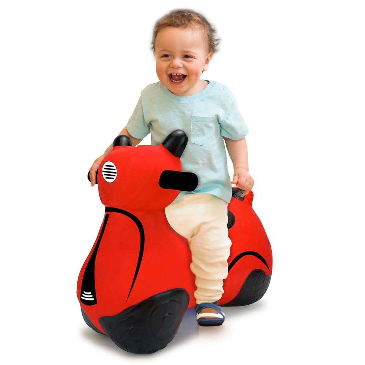 Małe dziecko jedzie na czerwonym motocyklu zabawką, uśmiechając się. Zabawka na białej powierzchni.