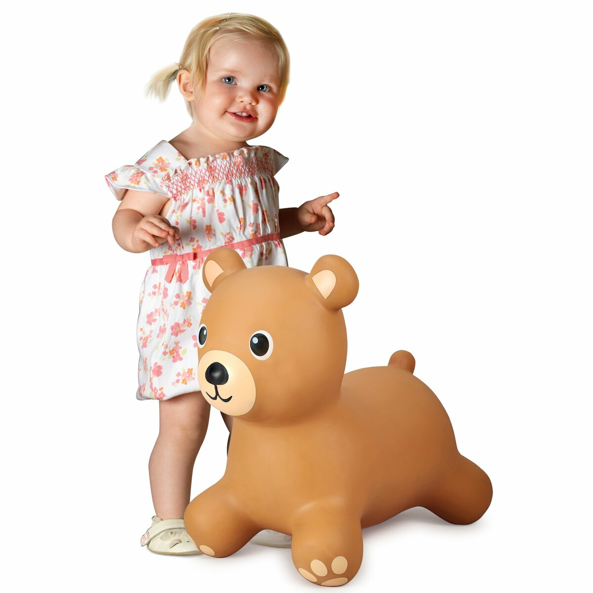 Una bambina è in piedi vicino a un giocattolo gonfiabile a forma di orso marrone. Indica e sorride.