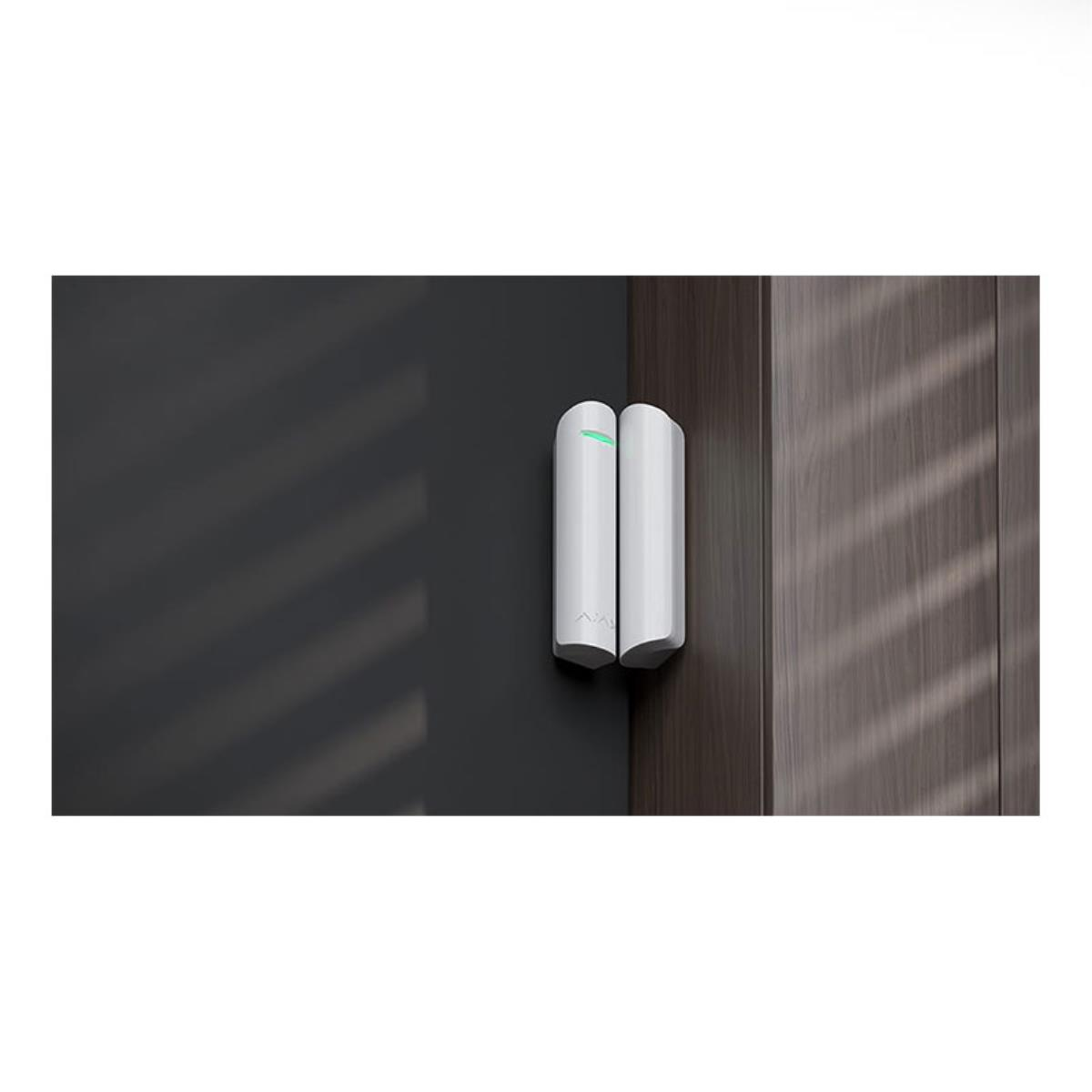 Conjunto de sensor de puerta blanco instalado en una puerta oscura y un marco de madera.