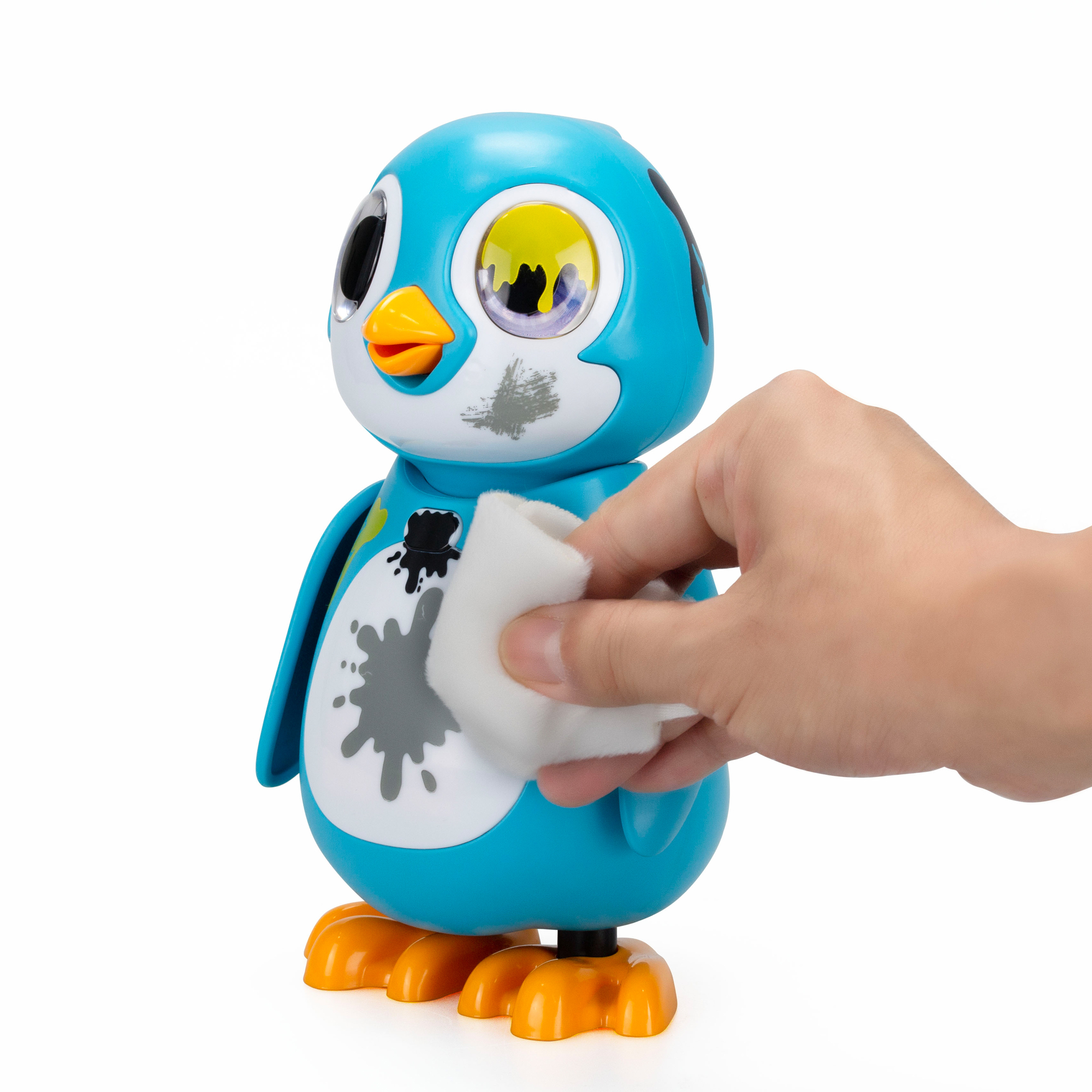 Un pinguino giocattolo con sporco sul viso che viene pulito con un panno da una mano.