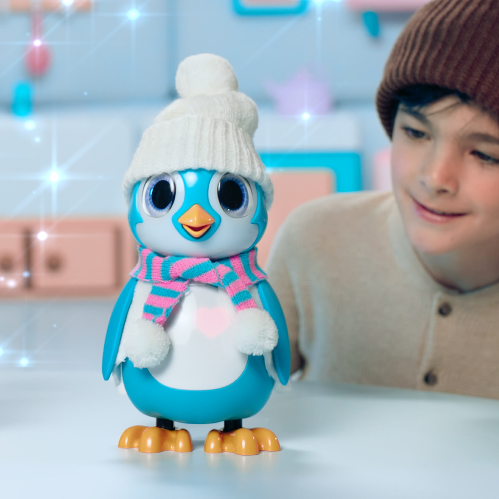 Un ragazzo sorride a un pinguino giocattolo, con un cappello bianco e una sciarpa rosa e blu.