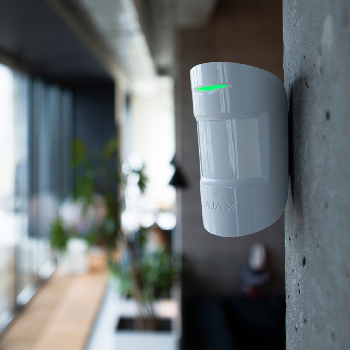 Sensor de alarma blanco en una pared. Luz verde en la parte superior. Diseño moderno.