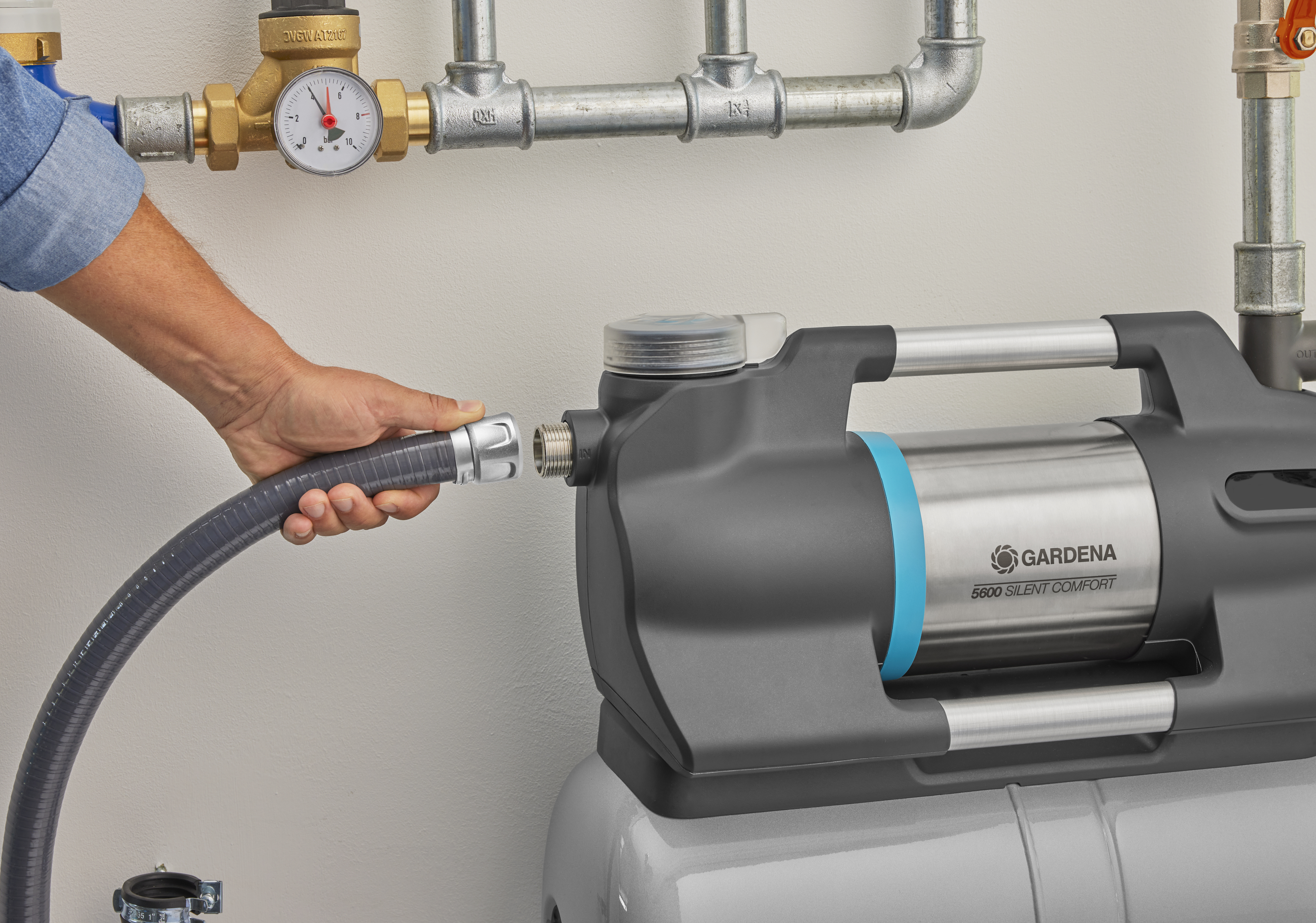 Osoba podłącza wąż do pompy ogrodowej.