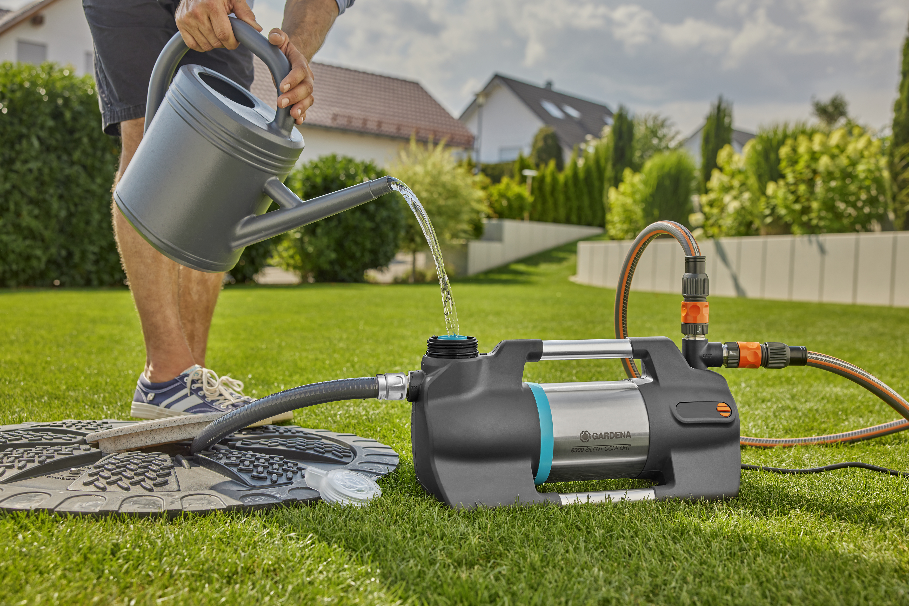 Osoba podlewa pompę ogrodową na zielonej trawie.