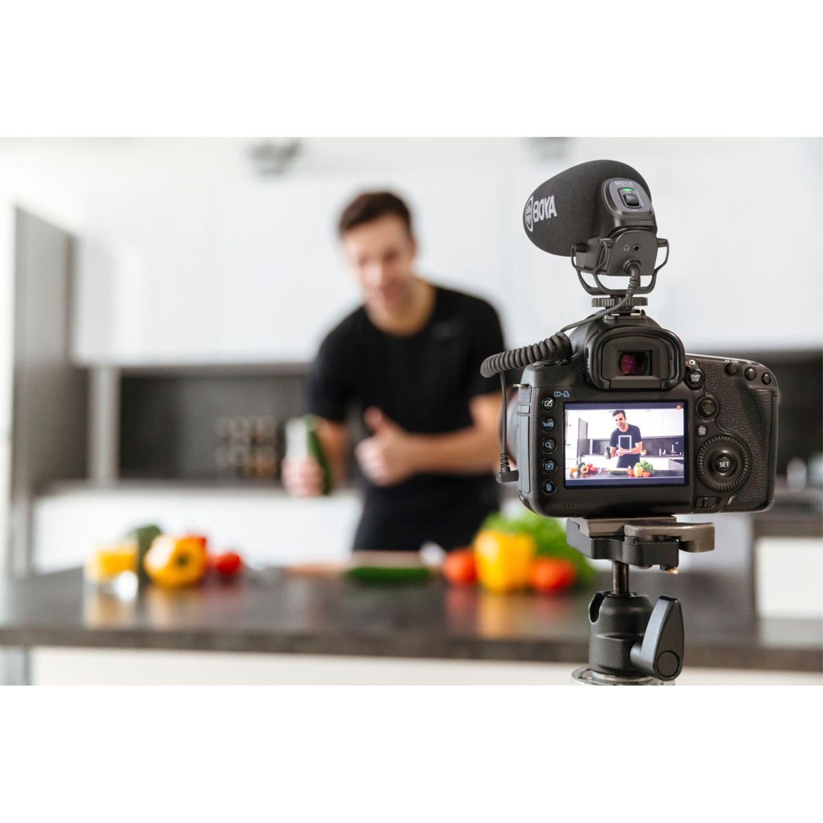 Mężczyzna gotuje w kuchni, nagrywając vloga za pomocą kamery i mikrofonu.