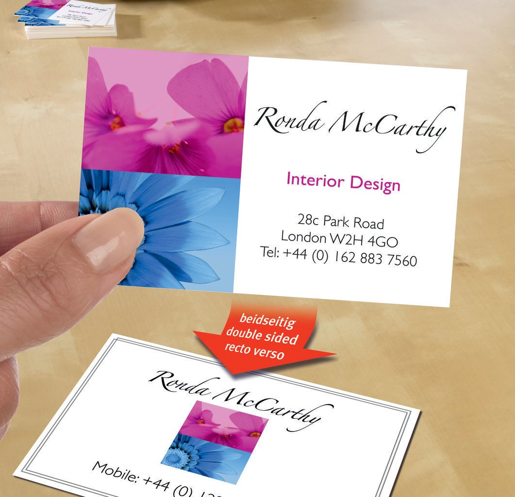 Hand, die eine Visitenkarte hält. Karte hat rosa und blaues Blumendesign mit Kontaktinfo.