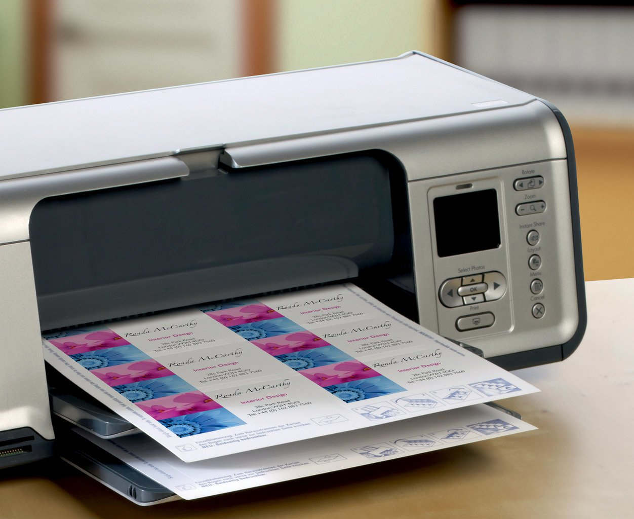 Drucker, der Visitenkarten druckt. Karten mit rosa und blauem Blumendesign werden gedruckt.