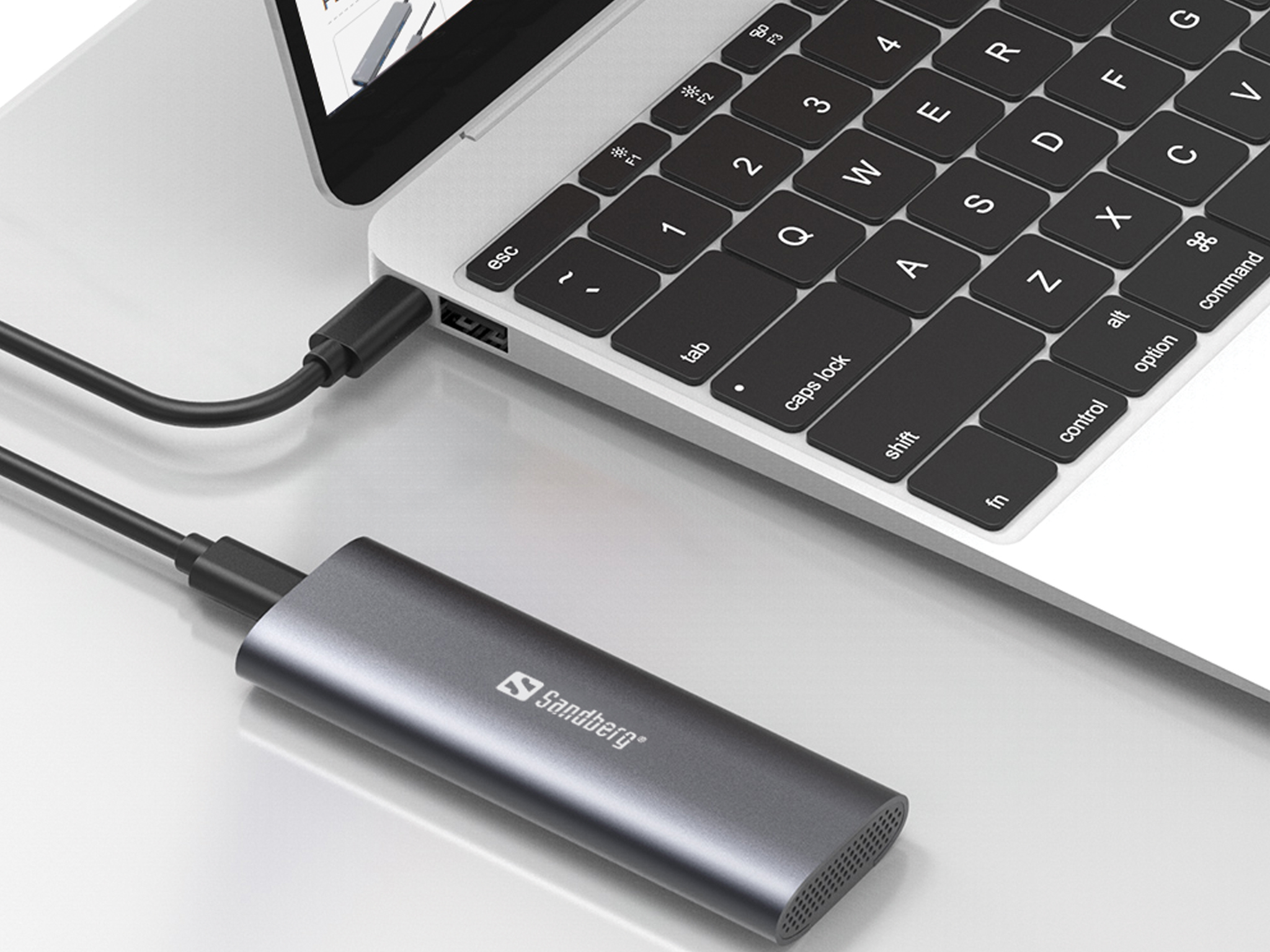 Disco rigido esterno grigio collegato a un laptop. Il laptop è aperto, mostrando la tastiera.
