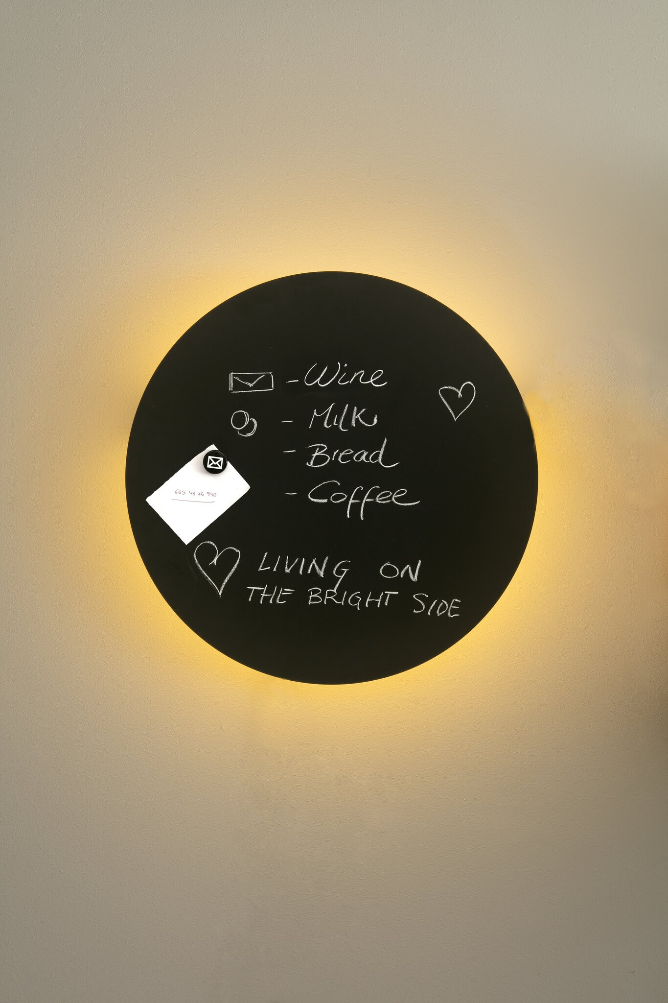Una lavagna rotonda e nera con le parole "Vino, Latte, Pane, Caffè" e "Vivere sul lato positivo".