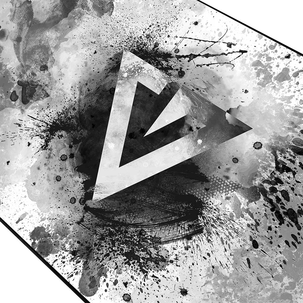 Zbliżenie czarno-białej podkładki pod mysz z białym logo 'V' i rozpryskami farby.