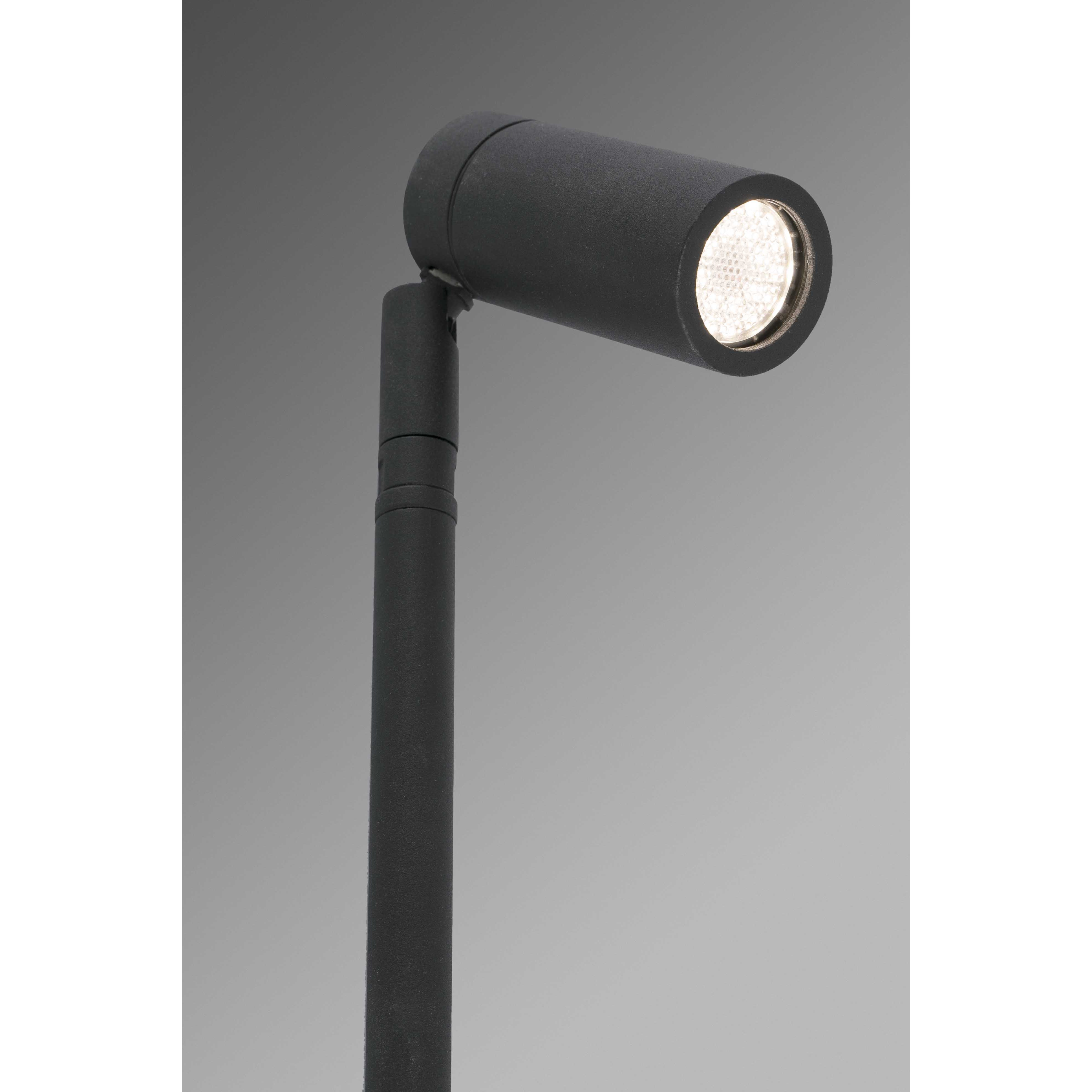 Faretto nero su un supporto. La luce è accesa, illuminando la parte anteriore della lampada.