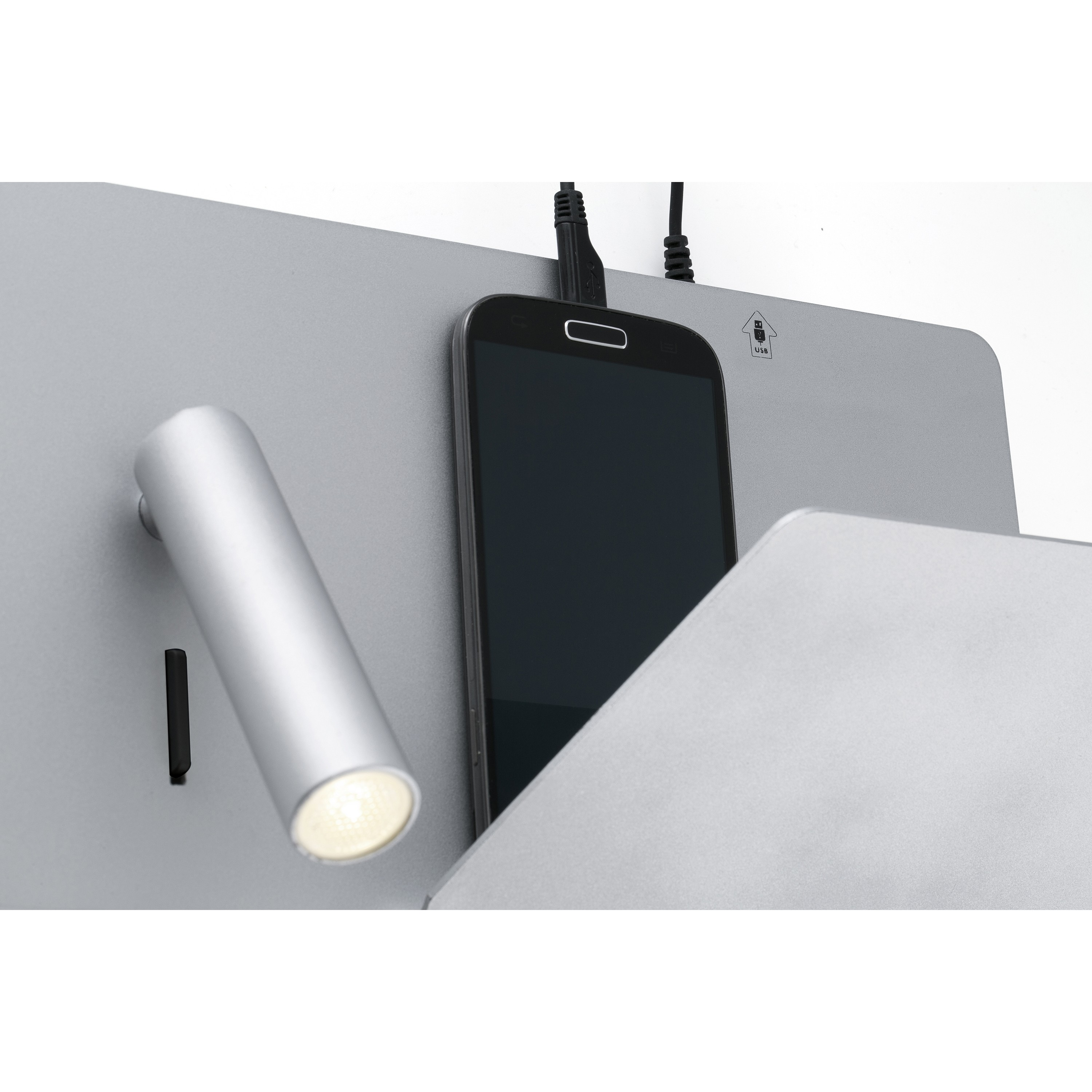 Un pannello argentato con uno smartphone collegato. Sono visibili anche una lampada e una porta USB.
