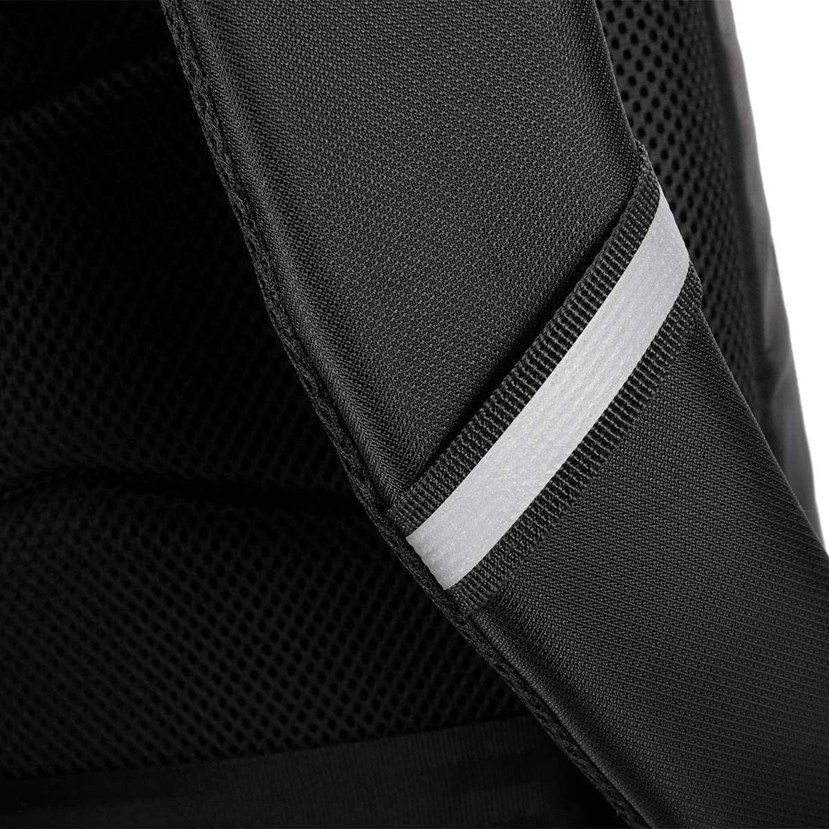 Zbliżenie czarnego paska plecaka z odblaskowym srebrnym paskiem. Siatka widoczna w tle.