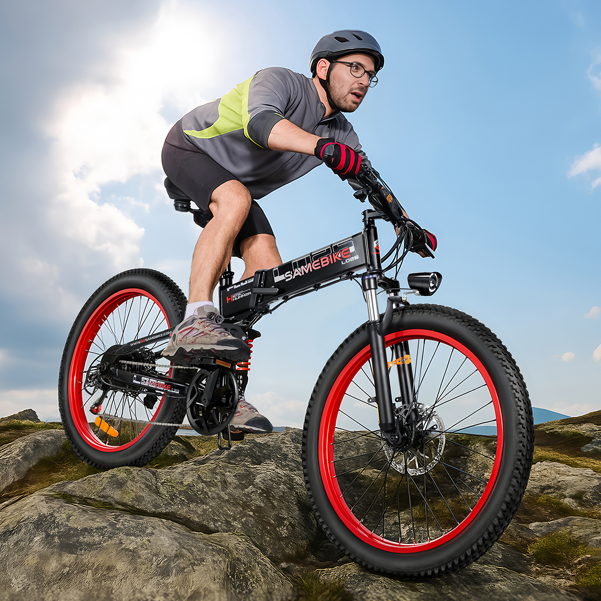 Mężczyzna jadący na składanym rowerze elektrycznym po skalistej ścieżce, w kasku i okularach, w słonecznym otoczeniu.