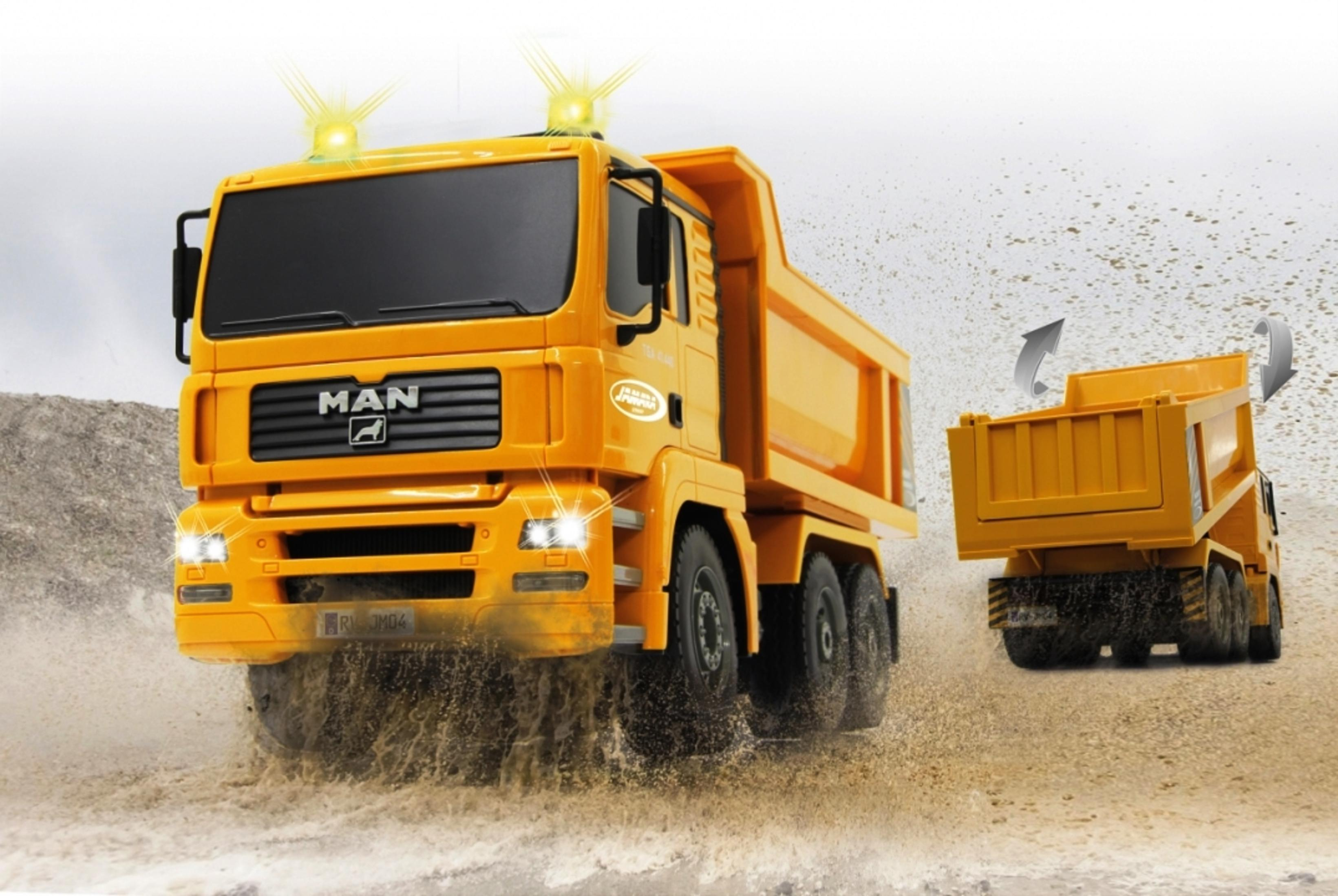 Żółta zabawka wywrotka jadąca przez wodę. Ciężarówka jest w ruchu, pluska wodą, za nią druga ciężarówka.