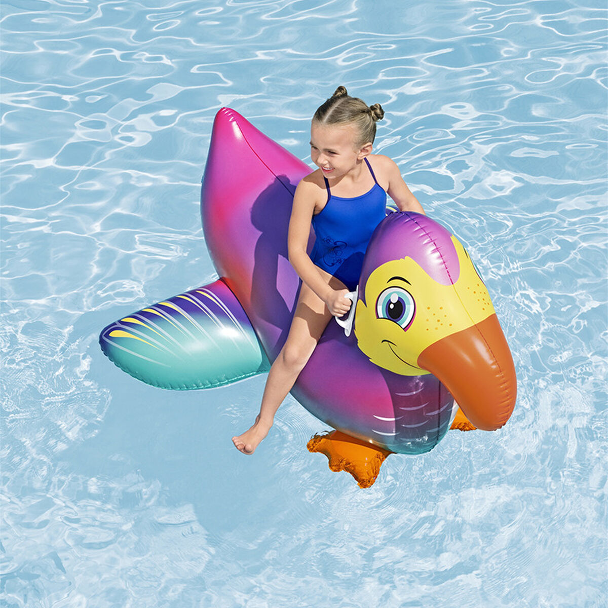 Ragazza su un galleggiante a forma di uccello gonfiabile in piscina. Sorride.