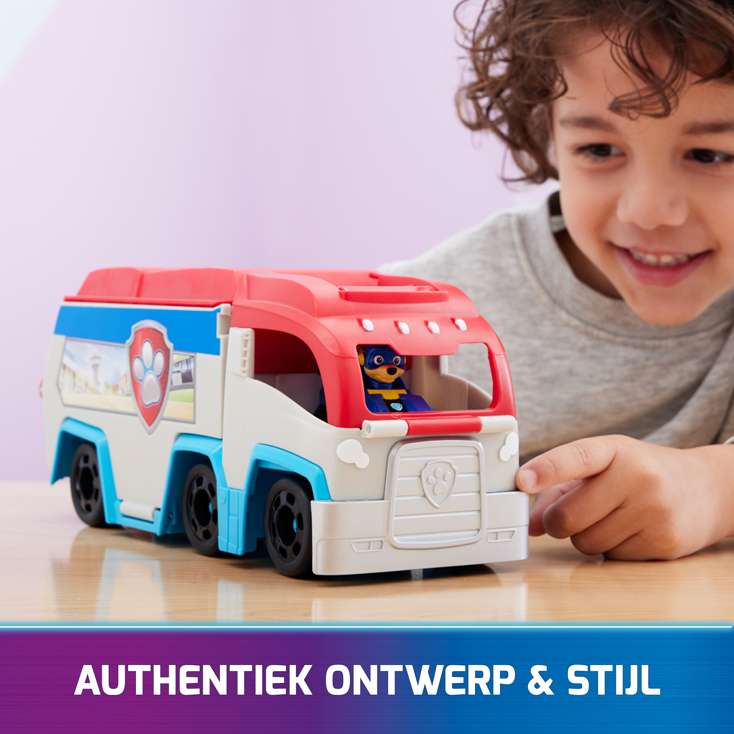 Un niño pequeño interactuando con un camión de juguete con un logo de Paw Patrol.