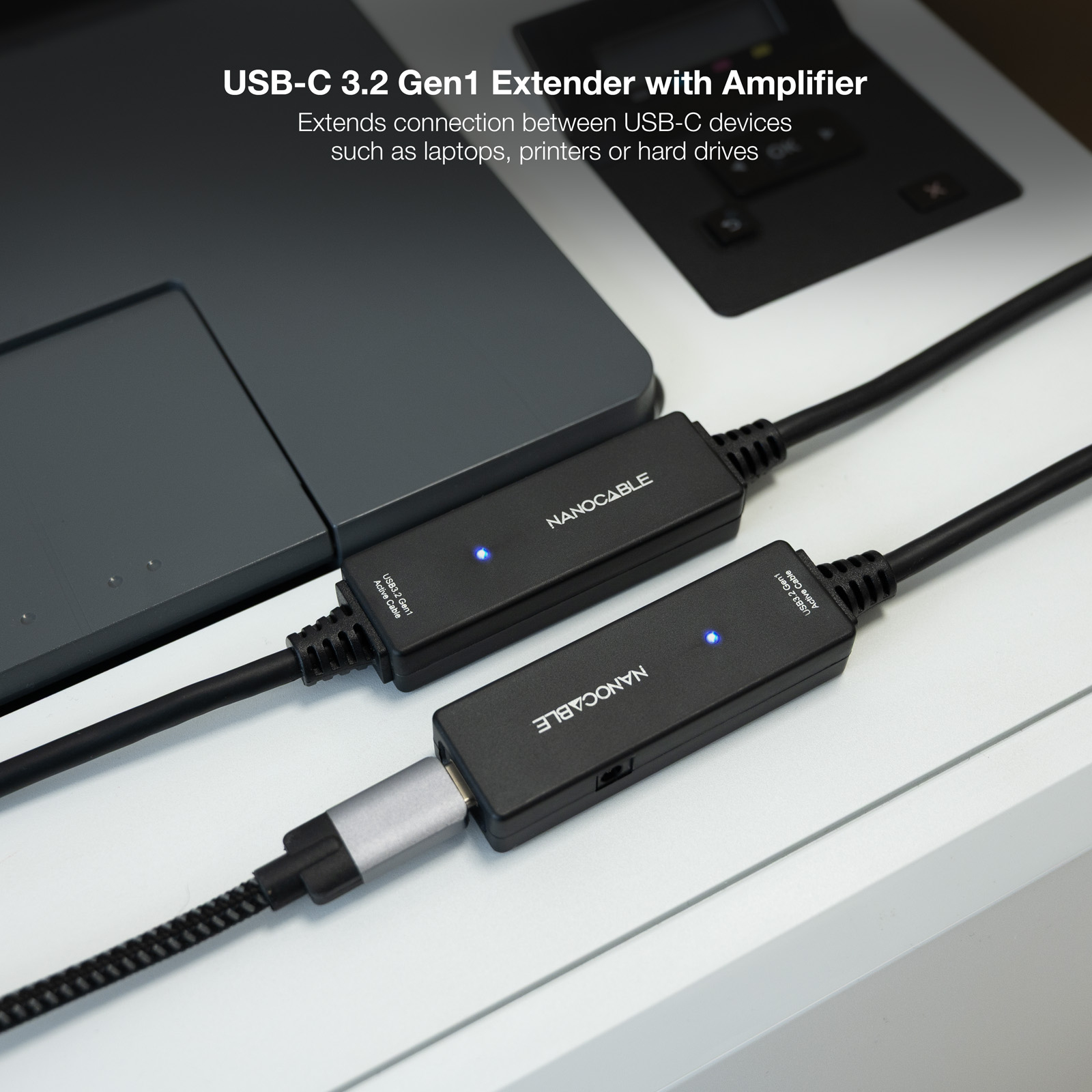 Twee zwarte USB-C extenders die met elkaar verbonden zijn, op een bureau met een laptop.