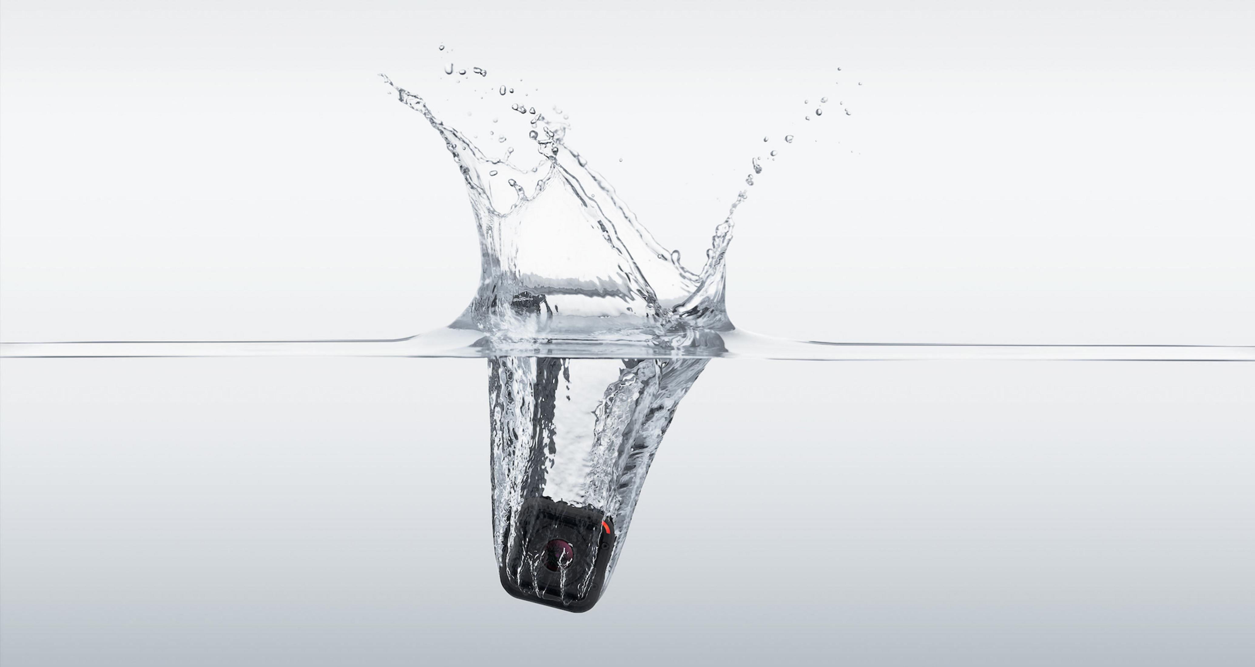 Eine schwarze Kamera im Wasser, Spritzer, weißer Hintergrund.