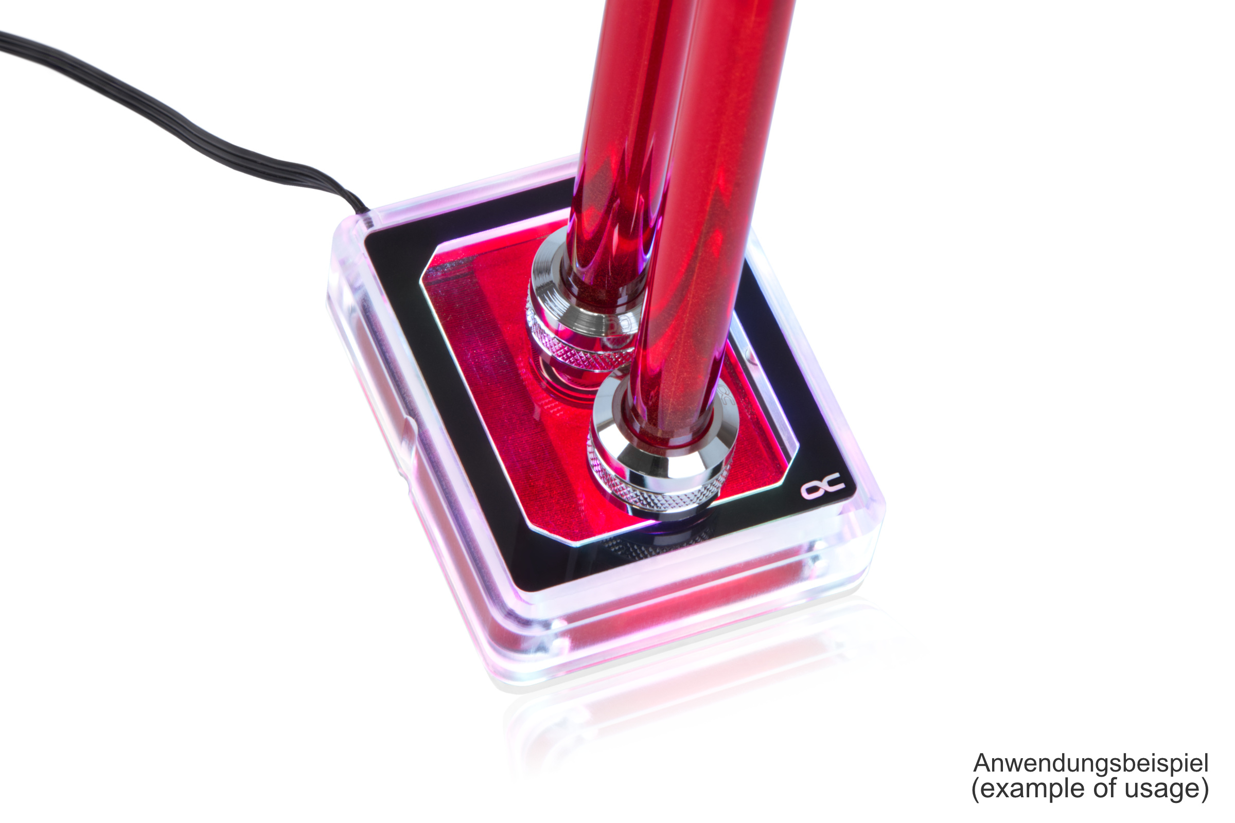 Waterblock per PC con due tubi rossi. Forma quadrata, custodia trasparente, sfondo bianco.