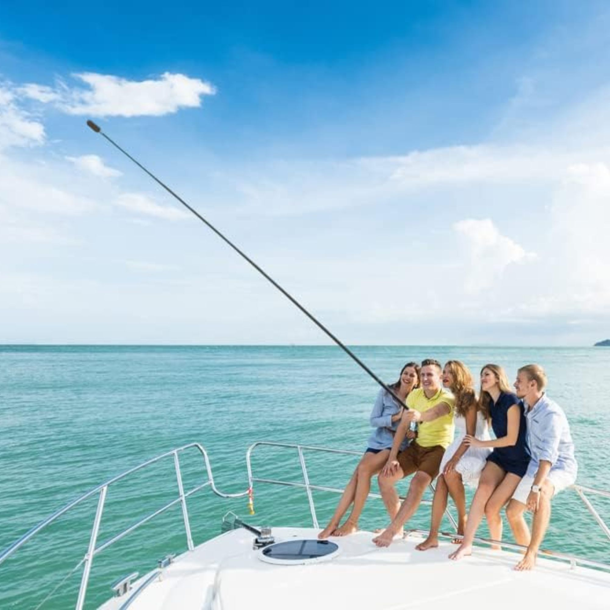 Grupa sześciu osób robiących selfie na jachcie. Niebieskie morze i niebo w tle.