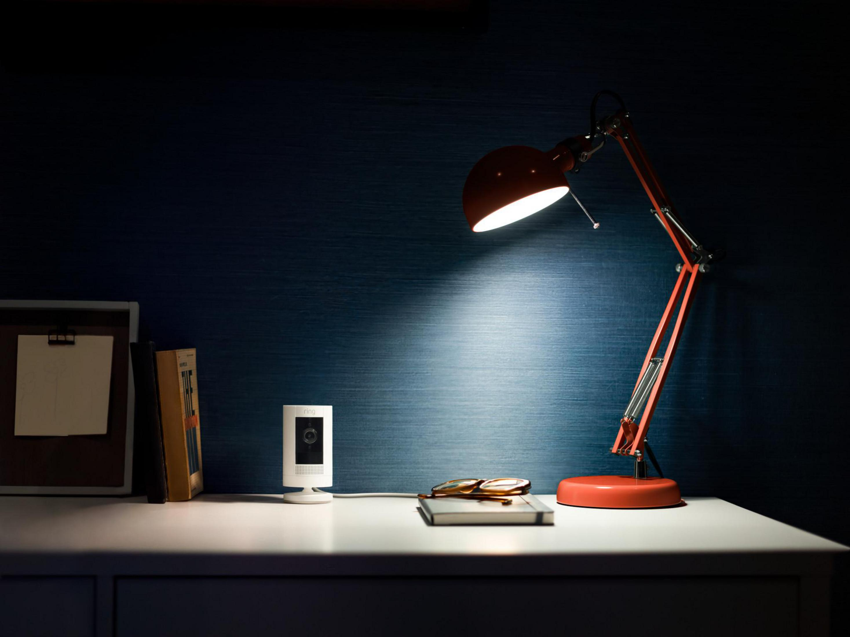 Desk with a lamp and security camera. There is a picture on the desk.