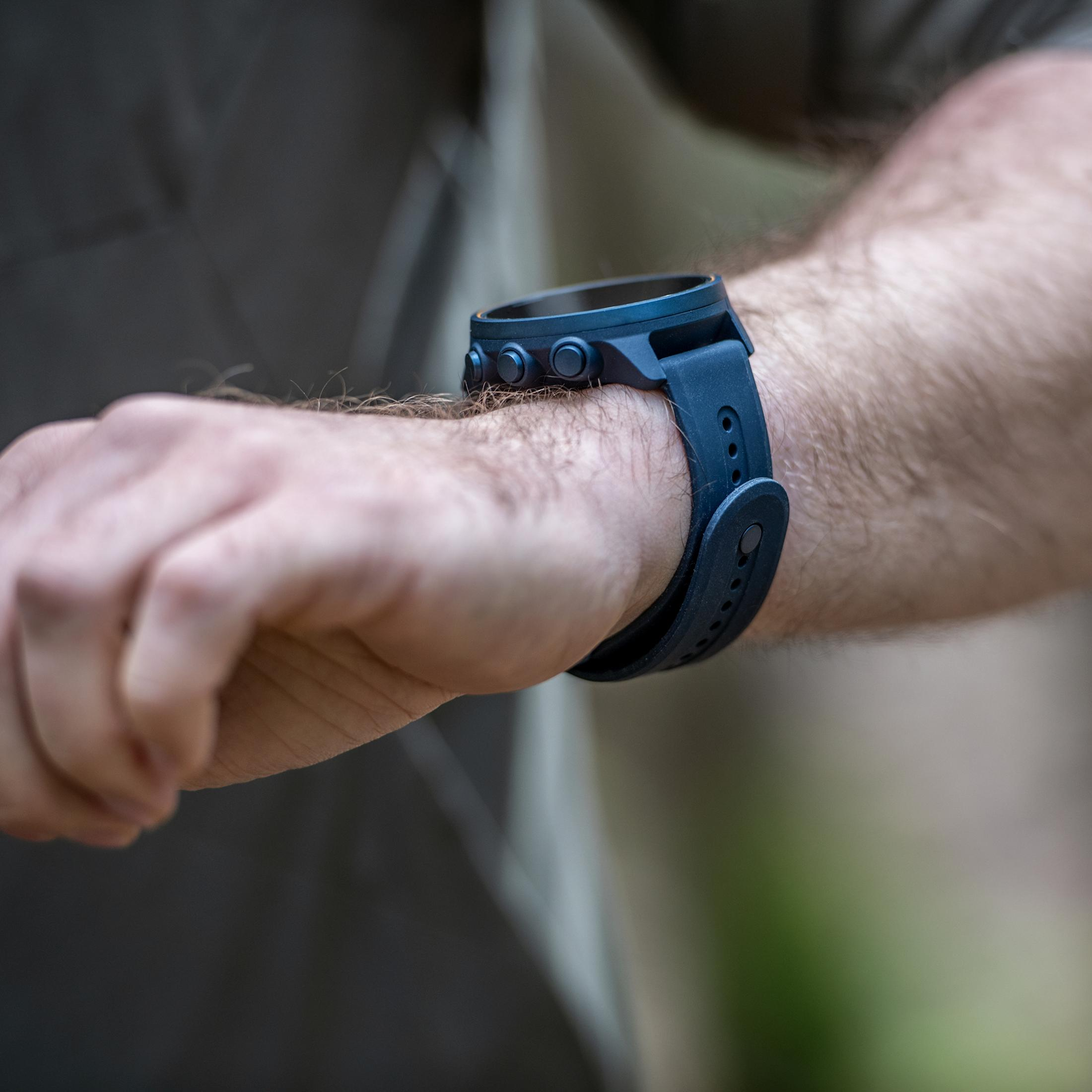 Das Handgelenk einer Person mit einer blauen Smartwatch mit drei Knöpfen.
