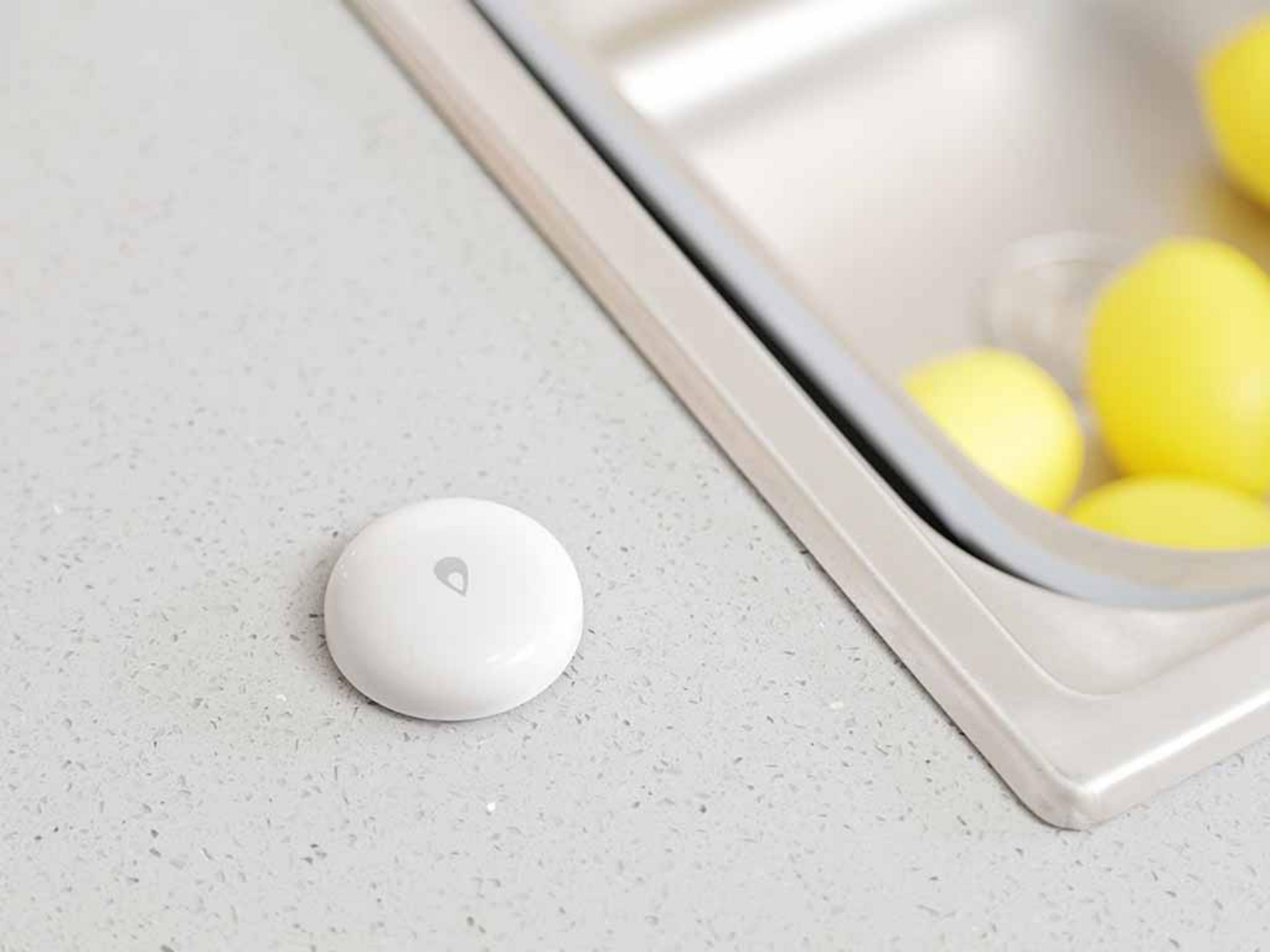 Biały czujnik wody z ikoną kropli na blacie.