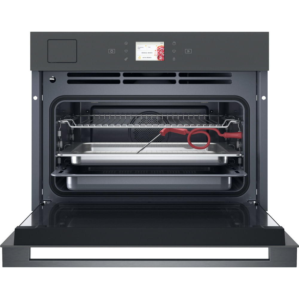 Un forno grigio scuro aperto con due teglie all'interno e un termometro per carne rosso.