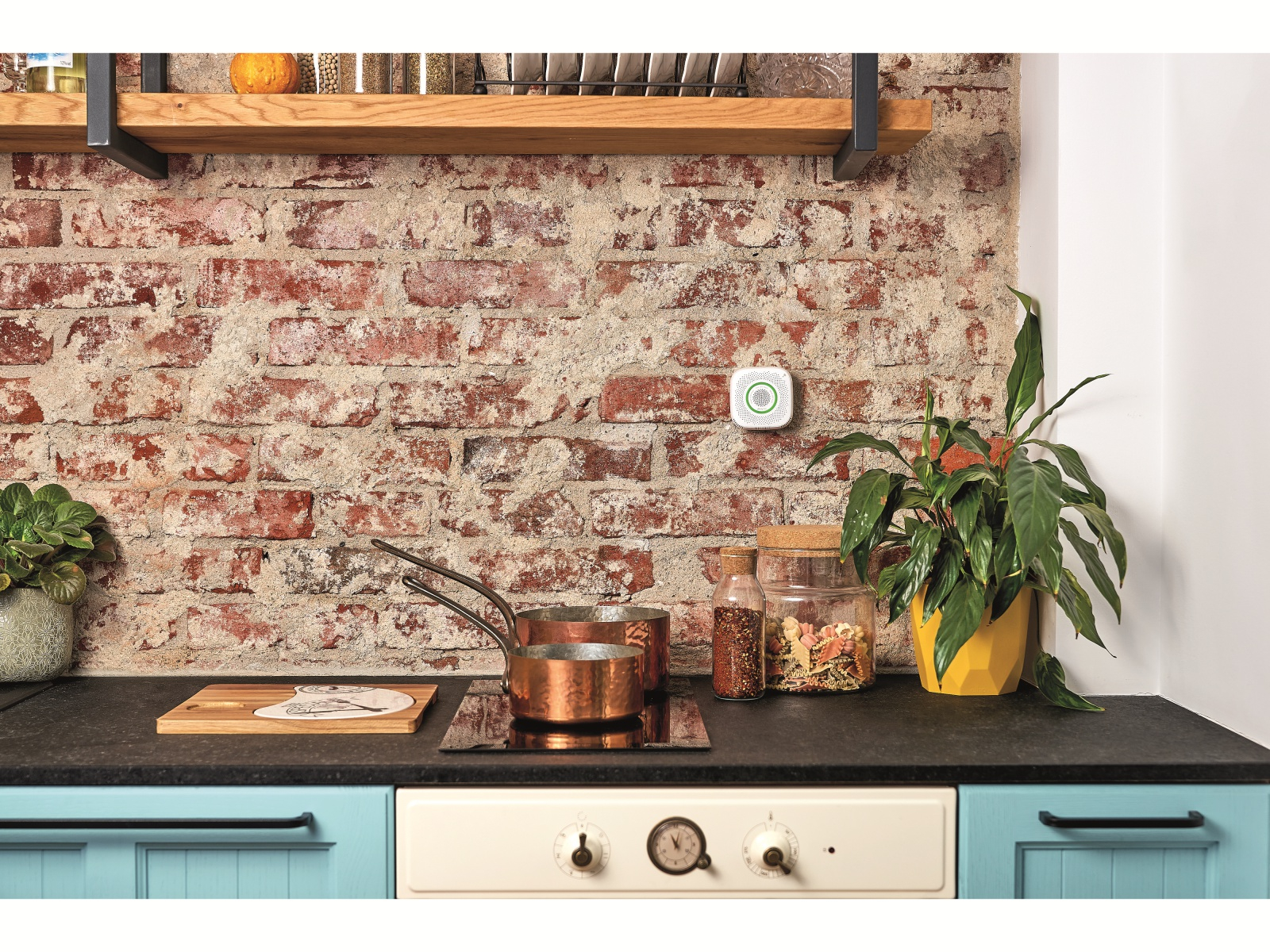 Scena kuchenna z ceglaną ścianą, płytą grzewczą i inteligentnym urządzeniem.