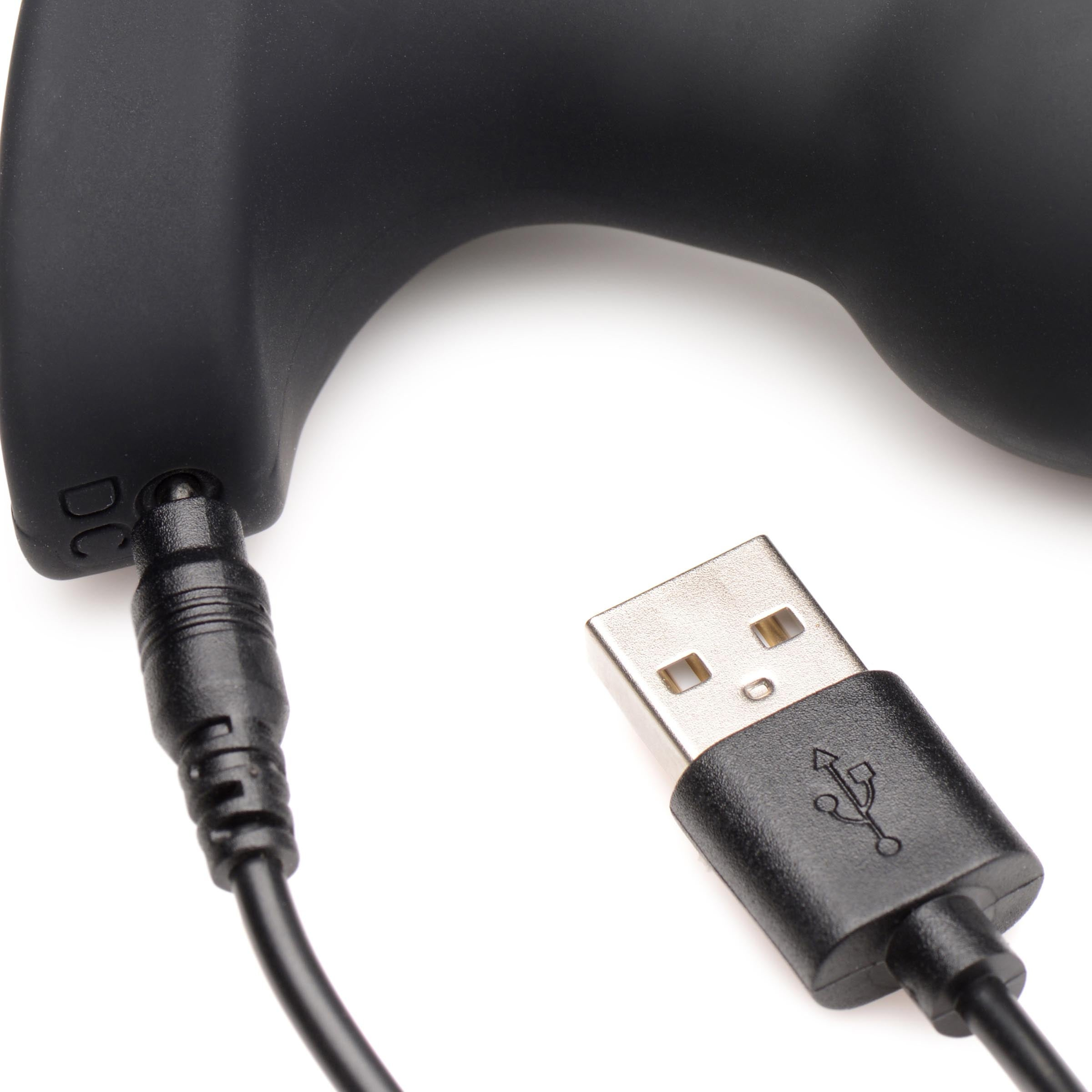 Zbliżenie czarnej zabawki erotycznej i czarnego kabla USB. Kabel jest podłączony.