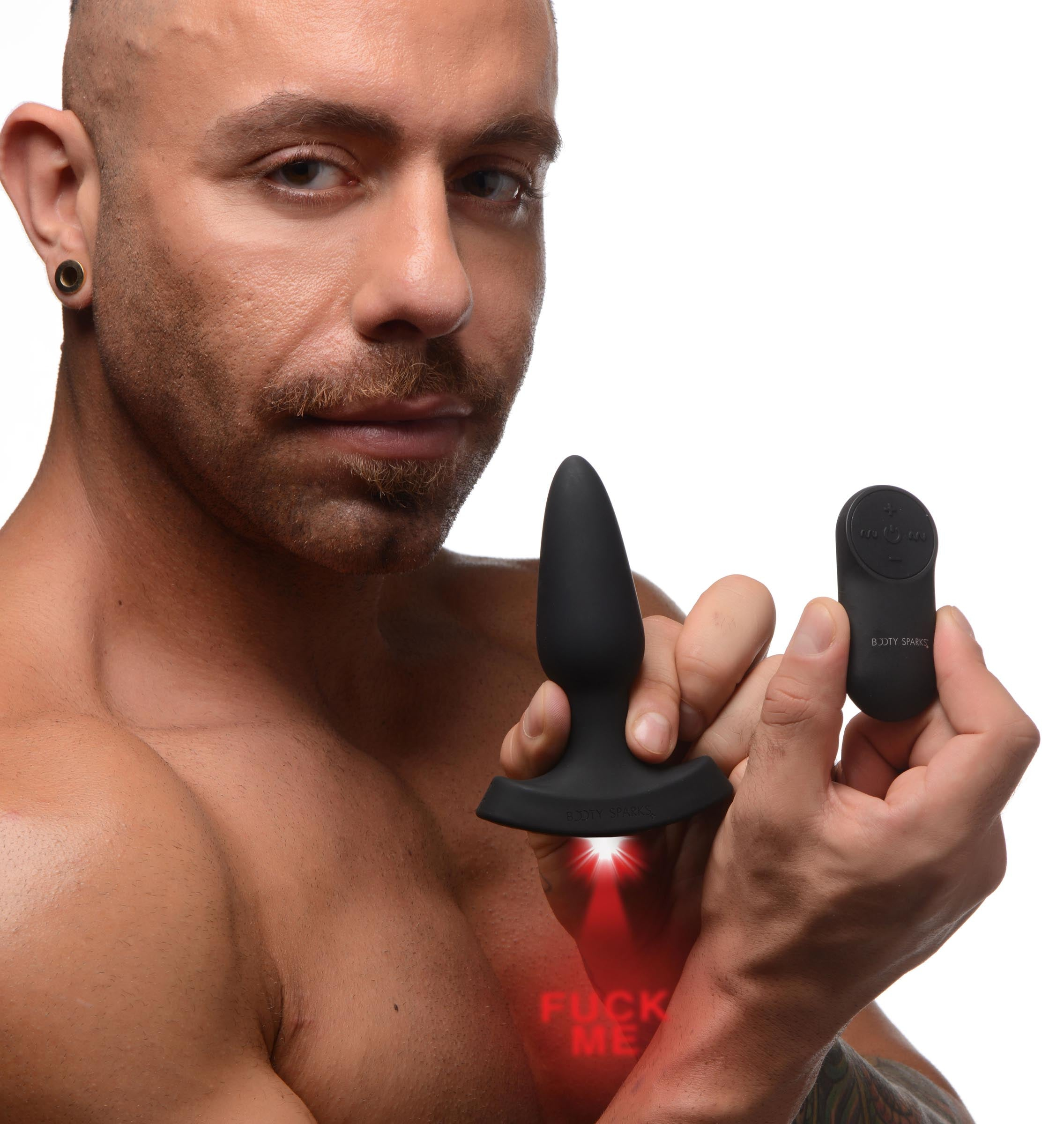 Mężczyzna trzymający czarną zabawkę erotyczną i pilota. Słowa "FUCK ME" są na nim wyświetlane. Izolowane.