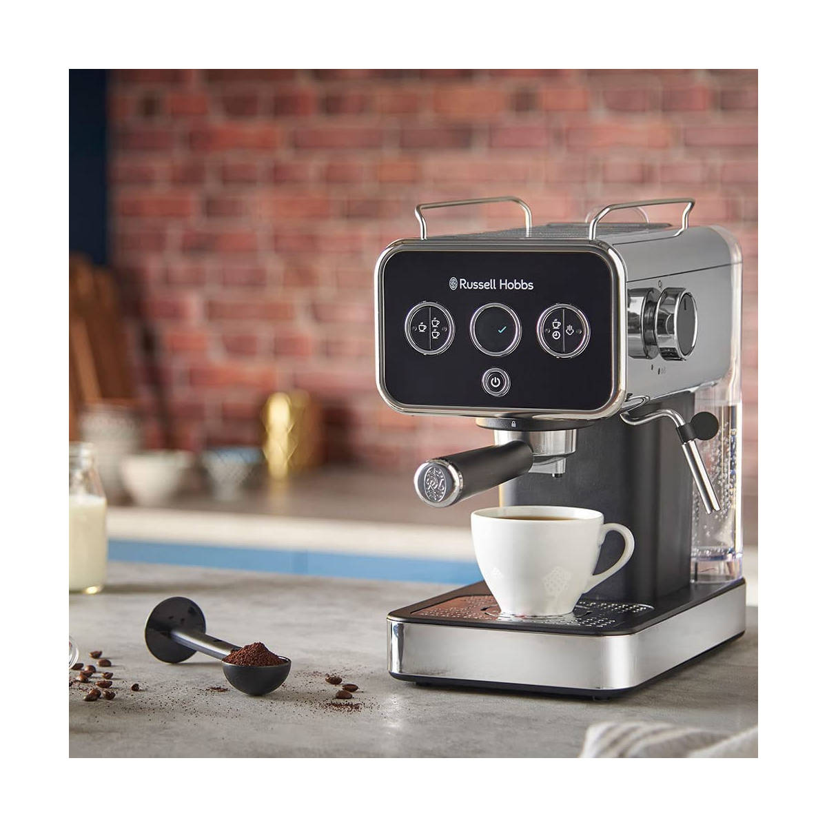 Bir fincan ile Russell Hobbs kahve makinesi. Kahve dökülüyor, yakınlarda kahve telvesi olan bir kaşık.