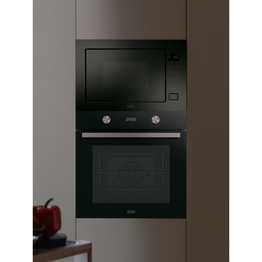 Combinazione forno a microonde e forno nera. Un peperone rosso è visibile sul bancone. Sfondo grigio.