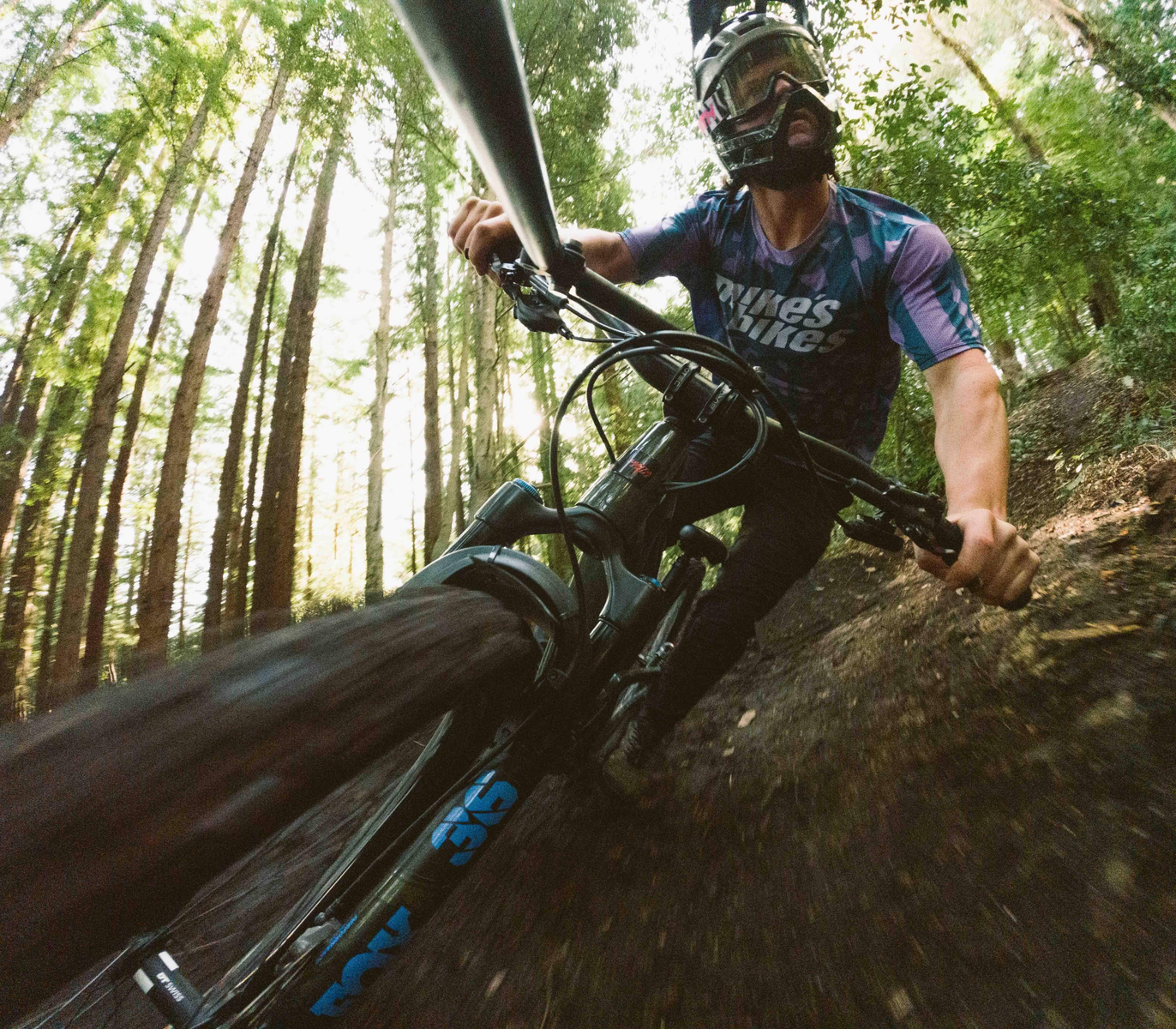 Kolarz górski jadący przez las, drzewa w tle. Widoczne rozmycie ruchu.