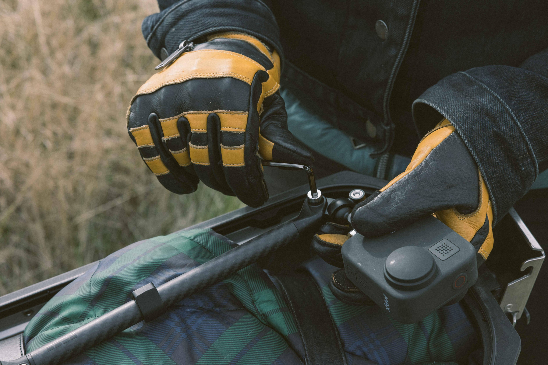 Ręce w rękawicach montujące kamerę na torbie.