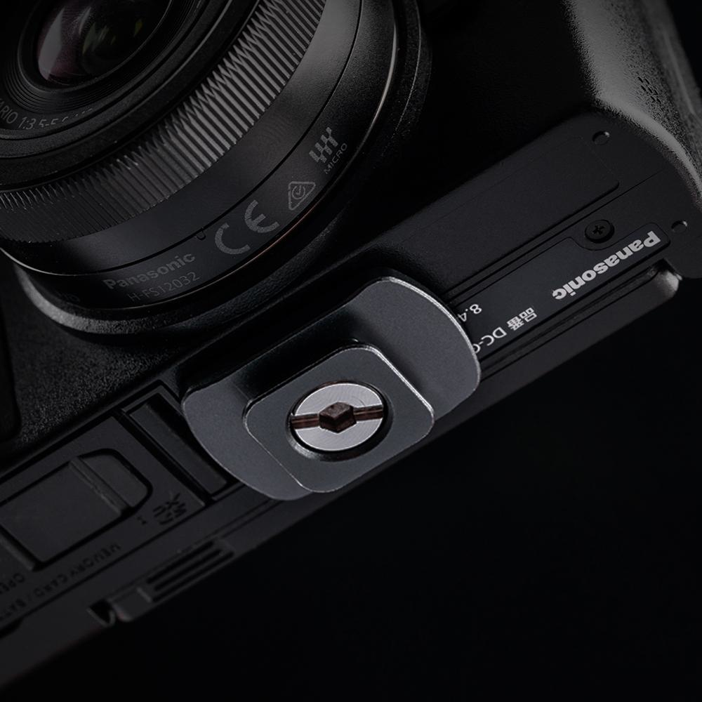 Zbliżenie mocowania aparatu przykręconego do czarnego korpusu aparatu Panasonic.