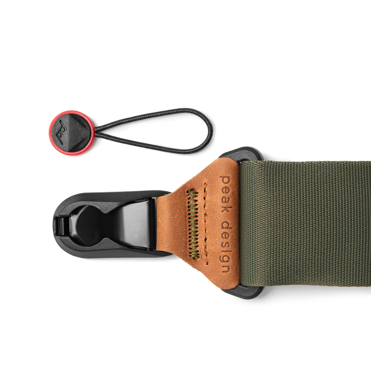 Czarny i zielony pasek do aparatu z czerwonym guzikiem z logo. Na skórze napis 'peak design'.