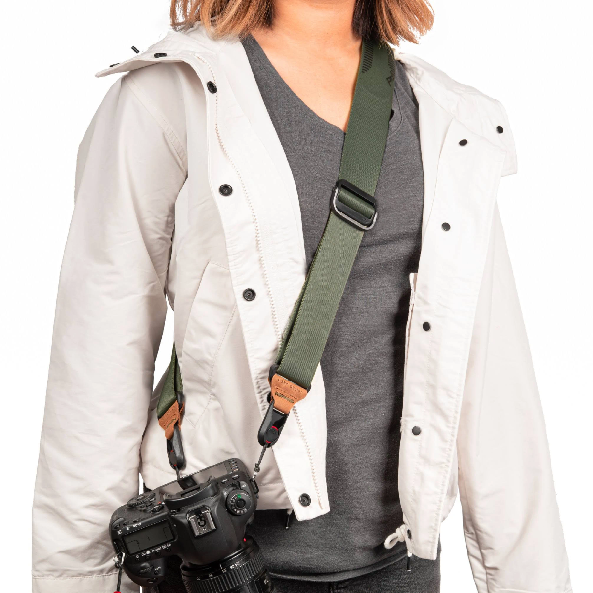 Kobieta w białej kurtce i aparat z zielonym paskiem.