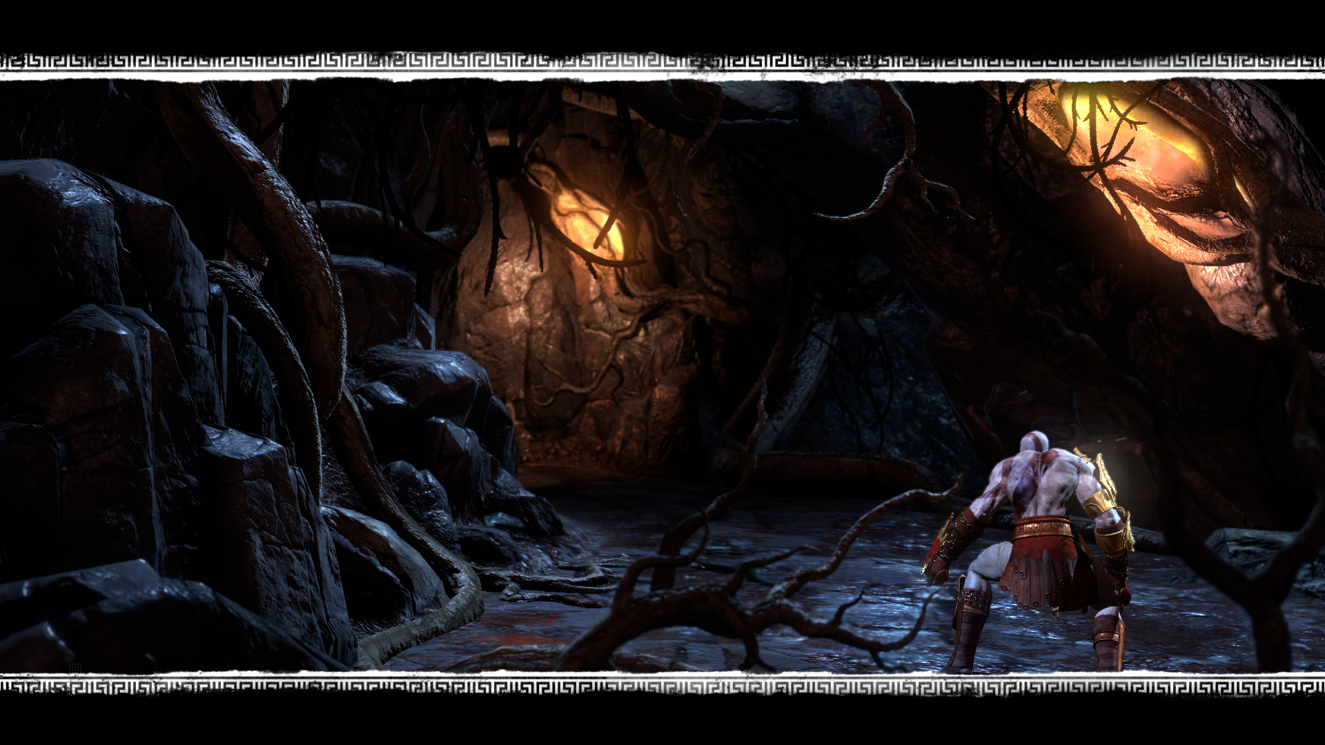 Scena di una grotta oscura. Un guerriero, Kratos, è in piedi. Ragni e luci incandescenti sono visibili.