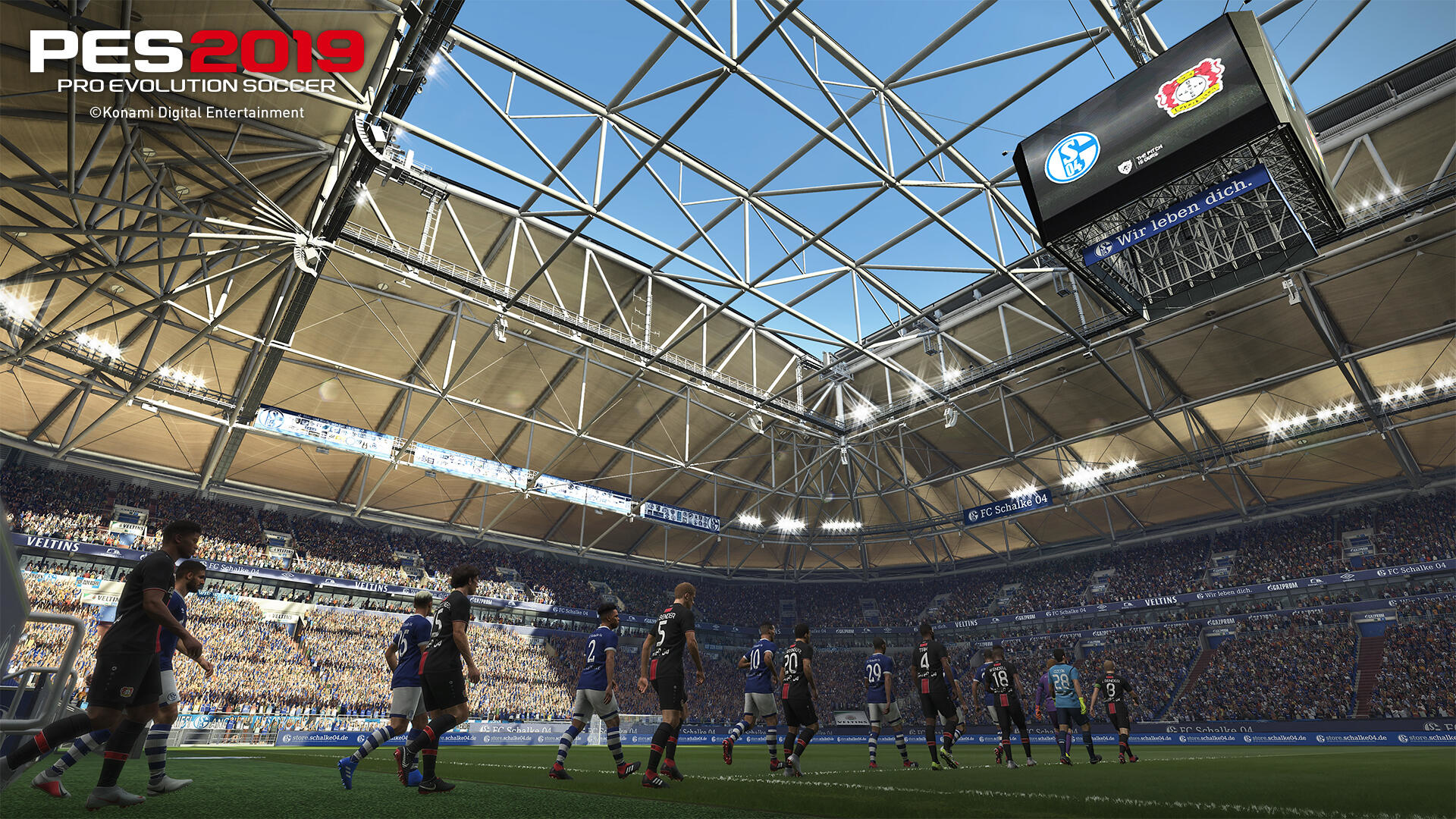 Stadion piłkarski wypełniony widzami podczas meczu, logo PES 2019 na górze.