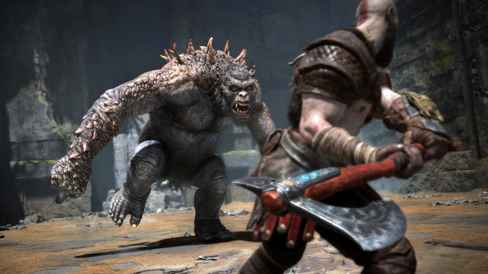 Obraz z God of War. Kratos walczy z dużym potworem. Scena walki w jaskini.