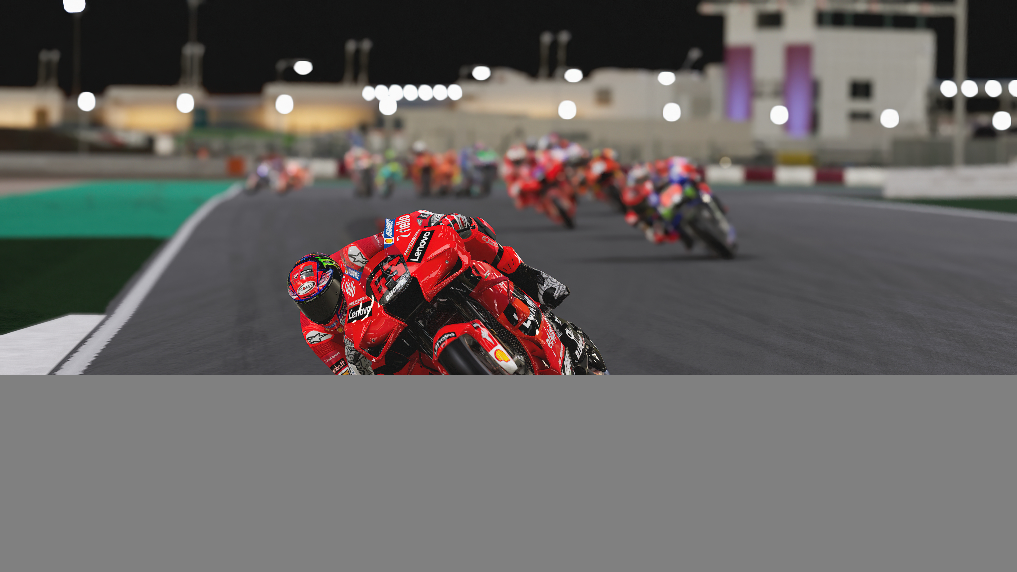 Motocykle ścigają się w nocy. Fokus jest na czerwonym motocyklu Ducati, prowadzącym stawkę.